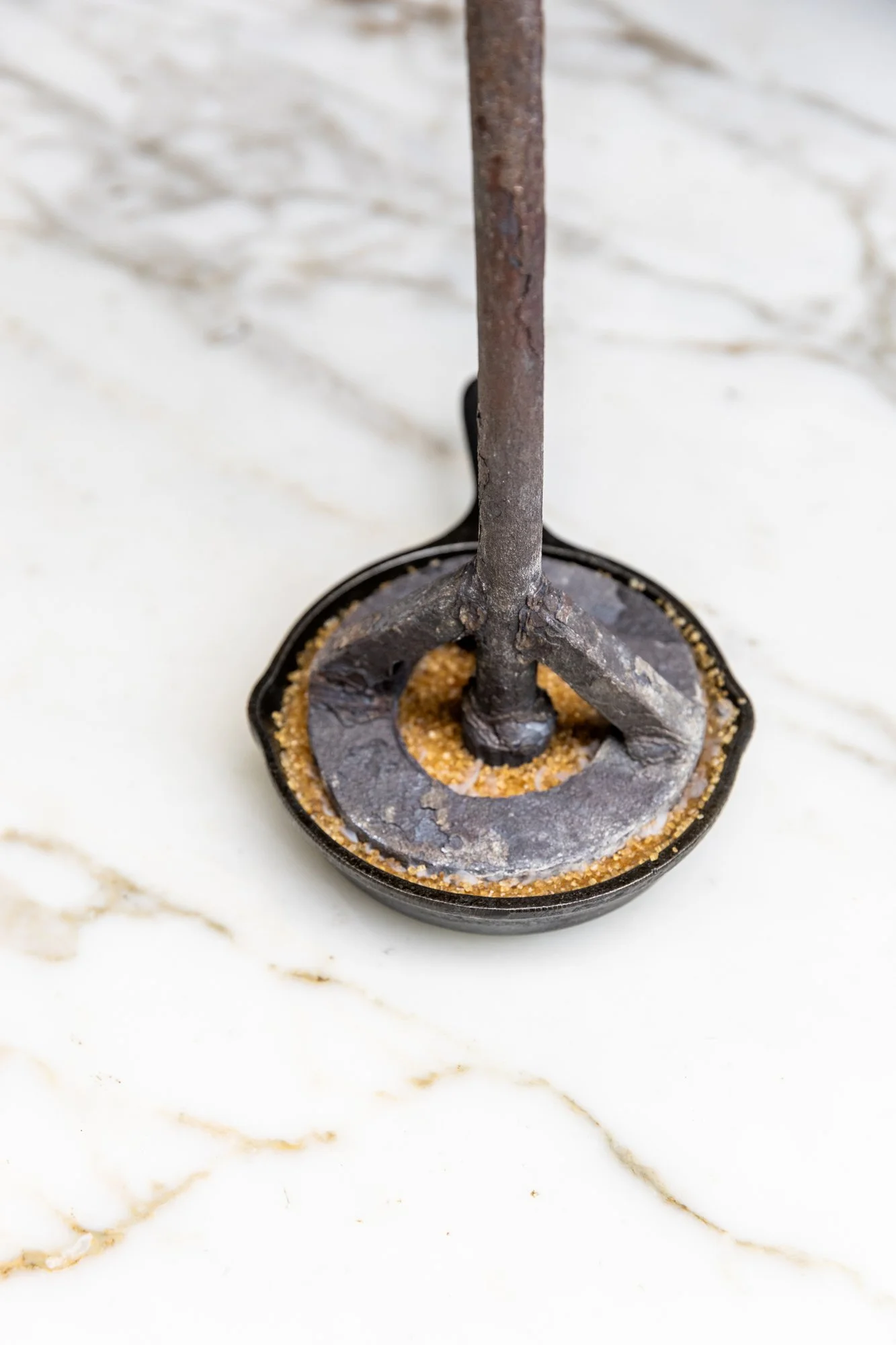 A vintage jar opener with a rusty handle on a white marble surface. Ovenbird Restaurant in Birmingham, Alabama.