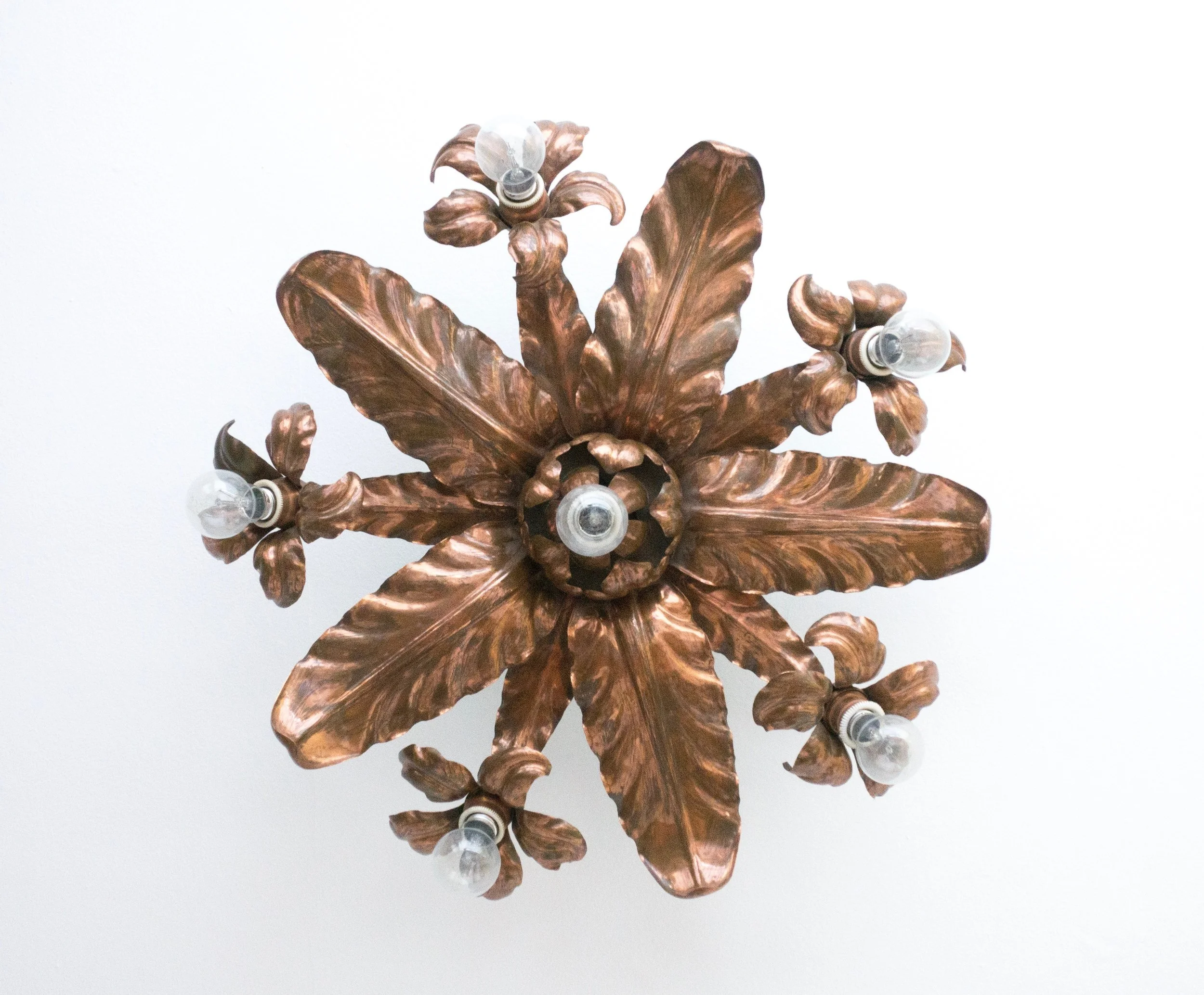 Repoussé Arts & Crafts period six light electrolier. Stylised leaves in star design with bulbs forming the centre of five alternate flowers. Fashioned from copper with a diameter of approximately 60cm and a 14cm drop from ceiling. AVAILABLE 