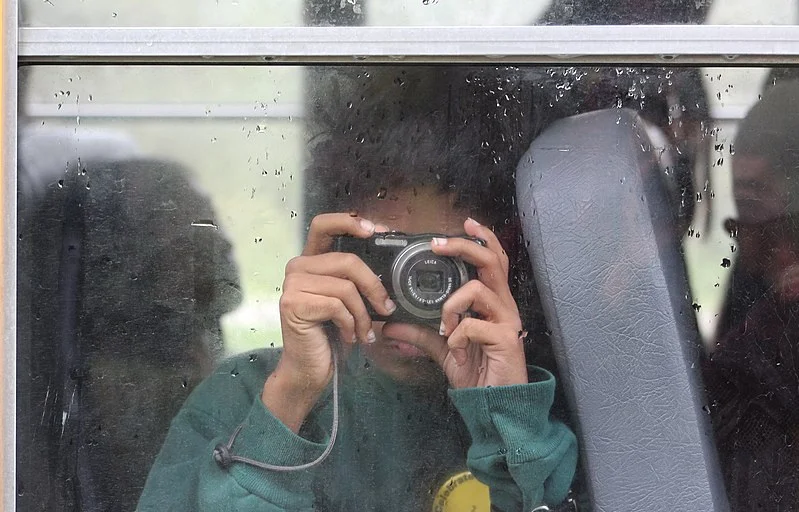 800px-Student_on_school_bus_holding_camera.jpg