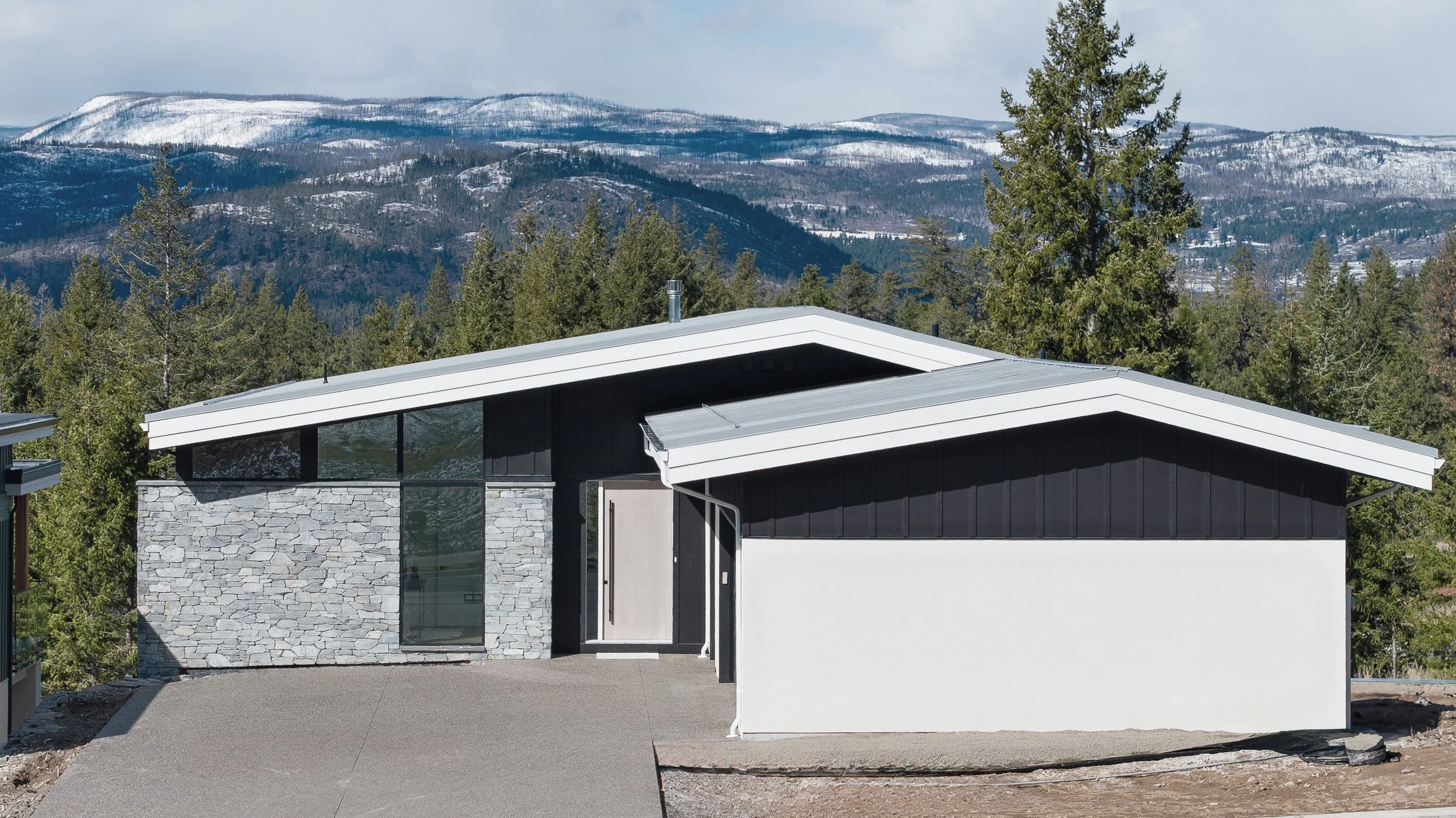 Exterior with a low roofline, stone and dark siding against the mountains, Terrace House, Predator Ridge