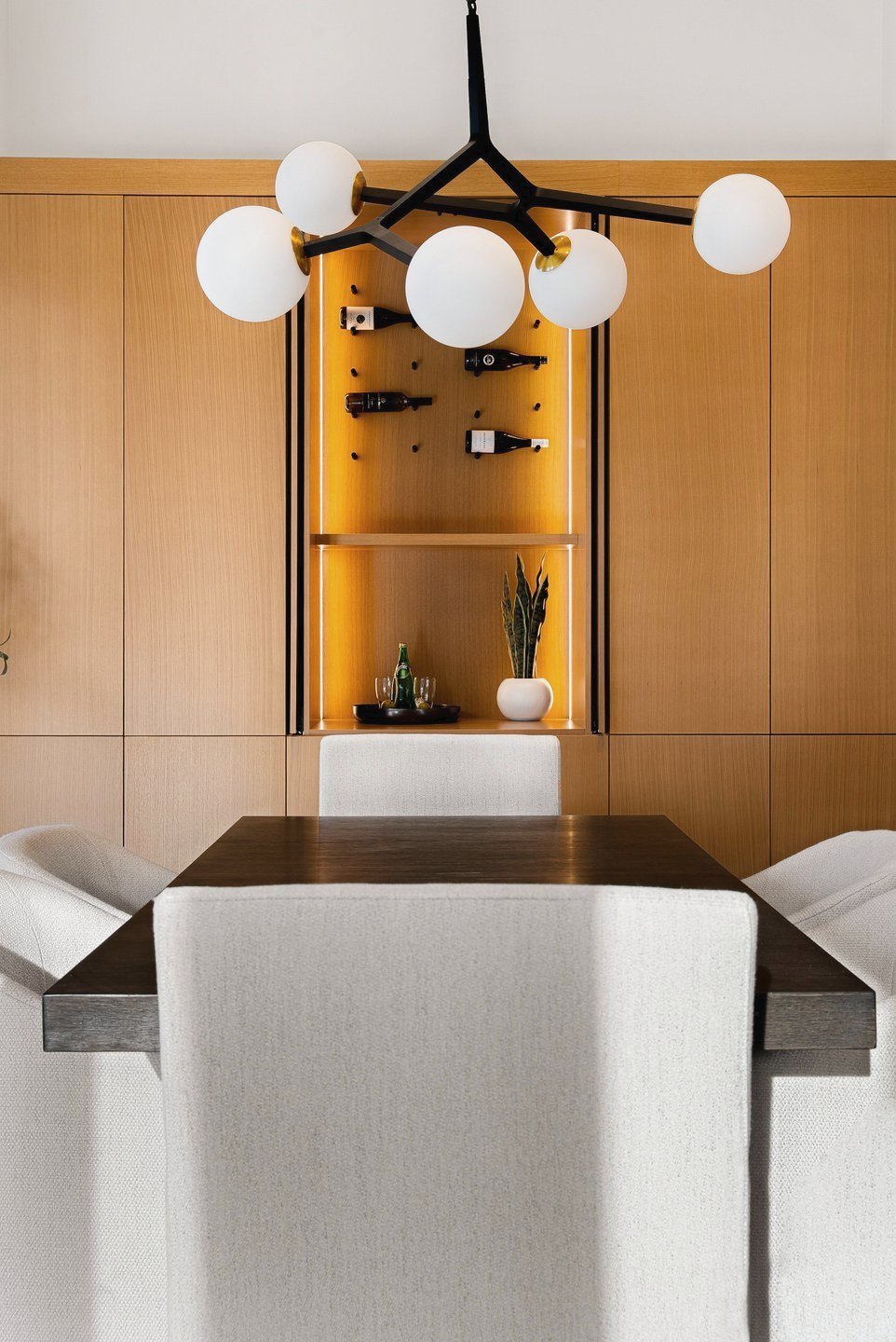 Globe chandelier over the dining table, with a lit oak niche behind, Fairway Rancher, Predator Ridge