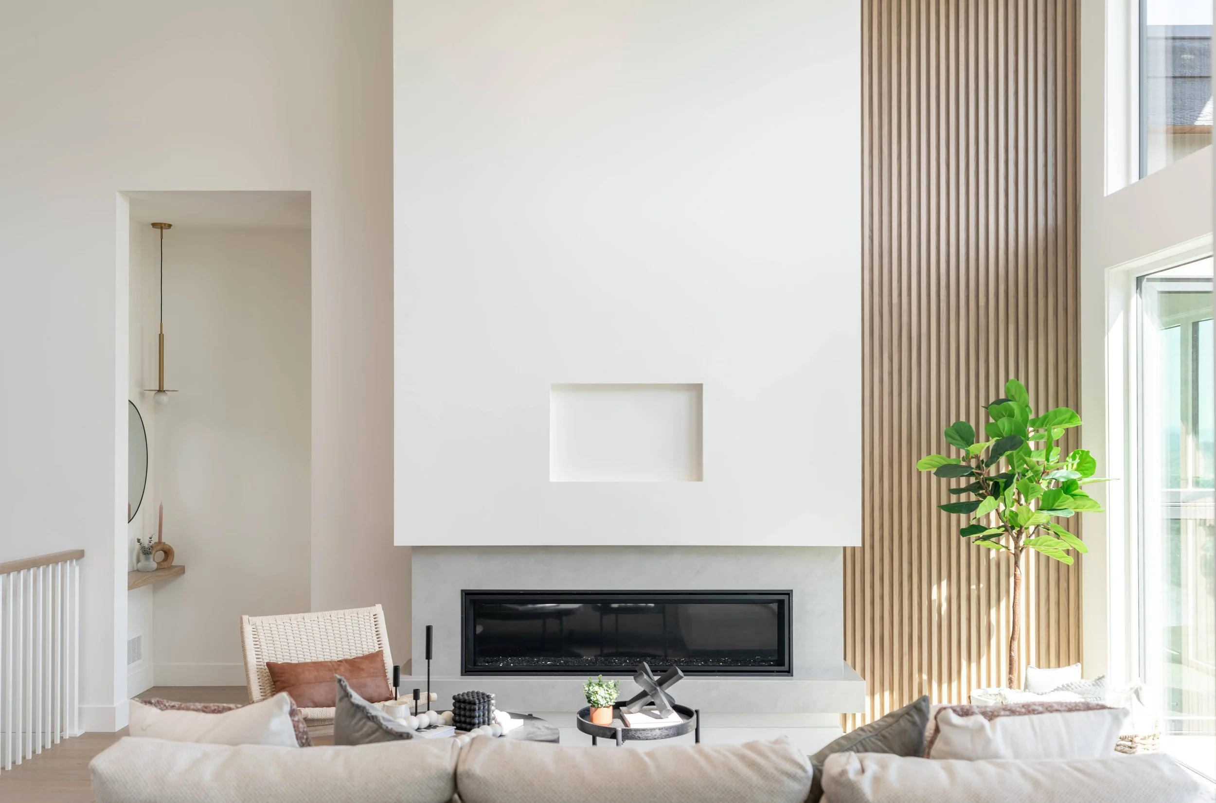 Linear fireplace wall with wood slat accent and sofa, Trailhead Showhome, Kelowna