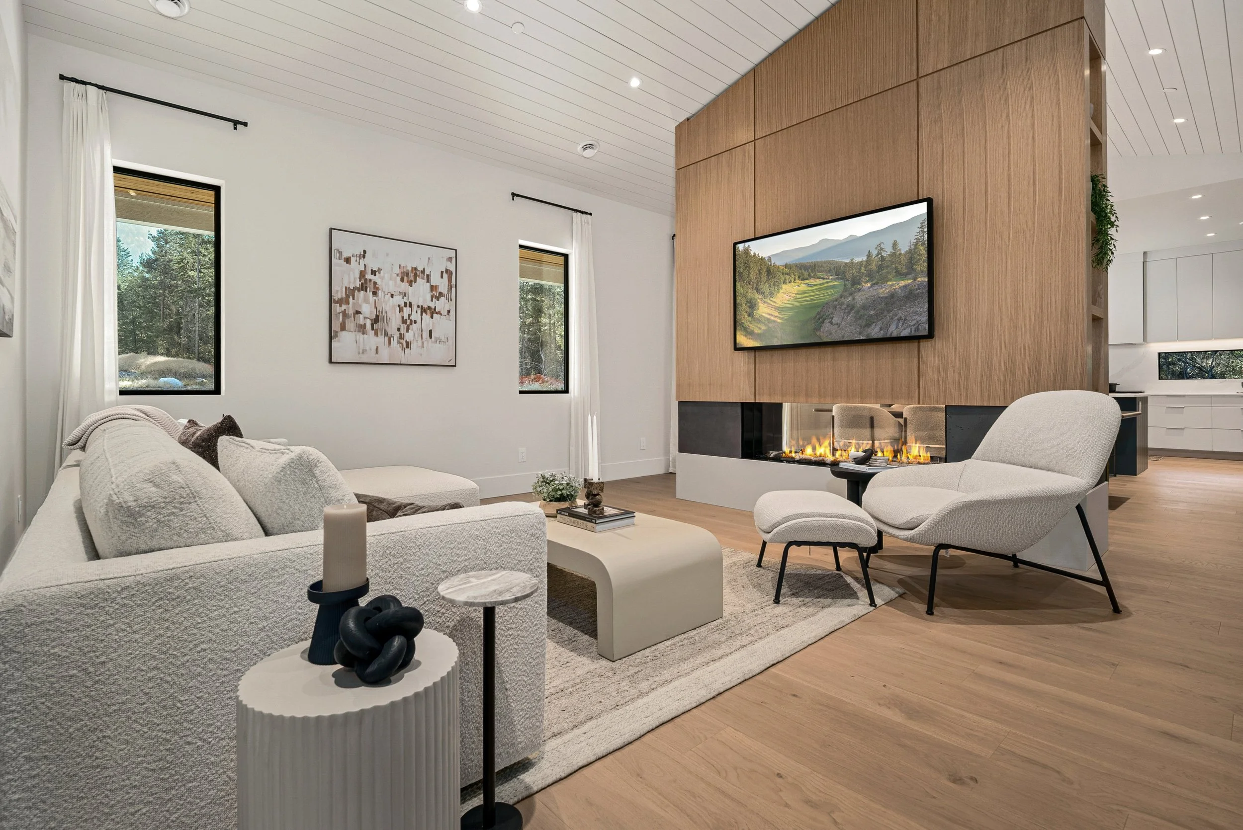 Living room fireplace wall at Woodside Showhome — vertical wood paneling, linear fire, and view through to the kitchen