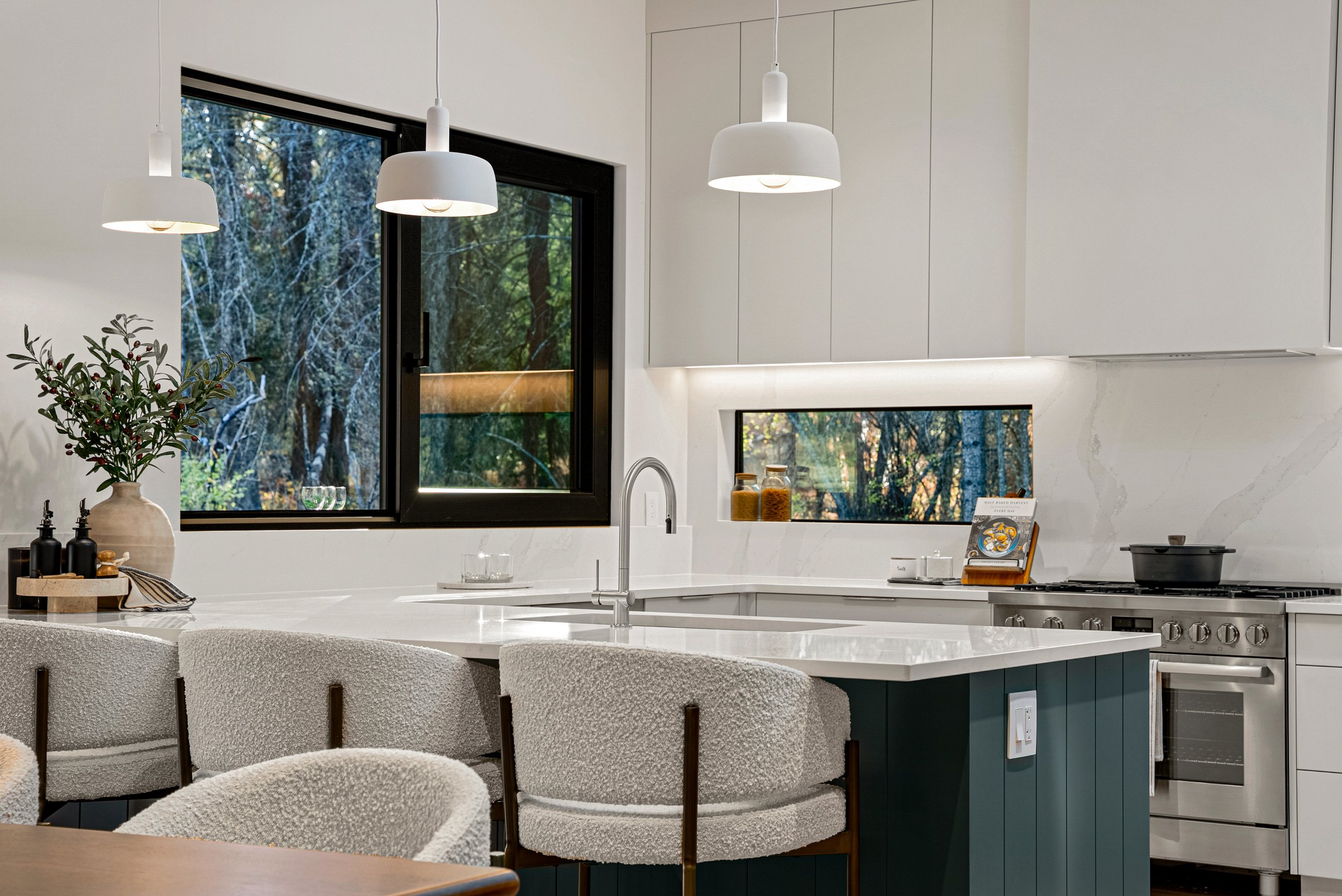 Kitchen island and pendants at Woodside Showhome with forest beyond the black-framed glass