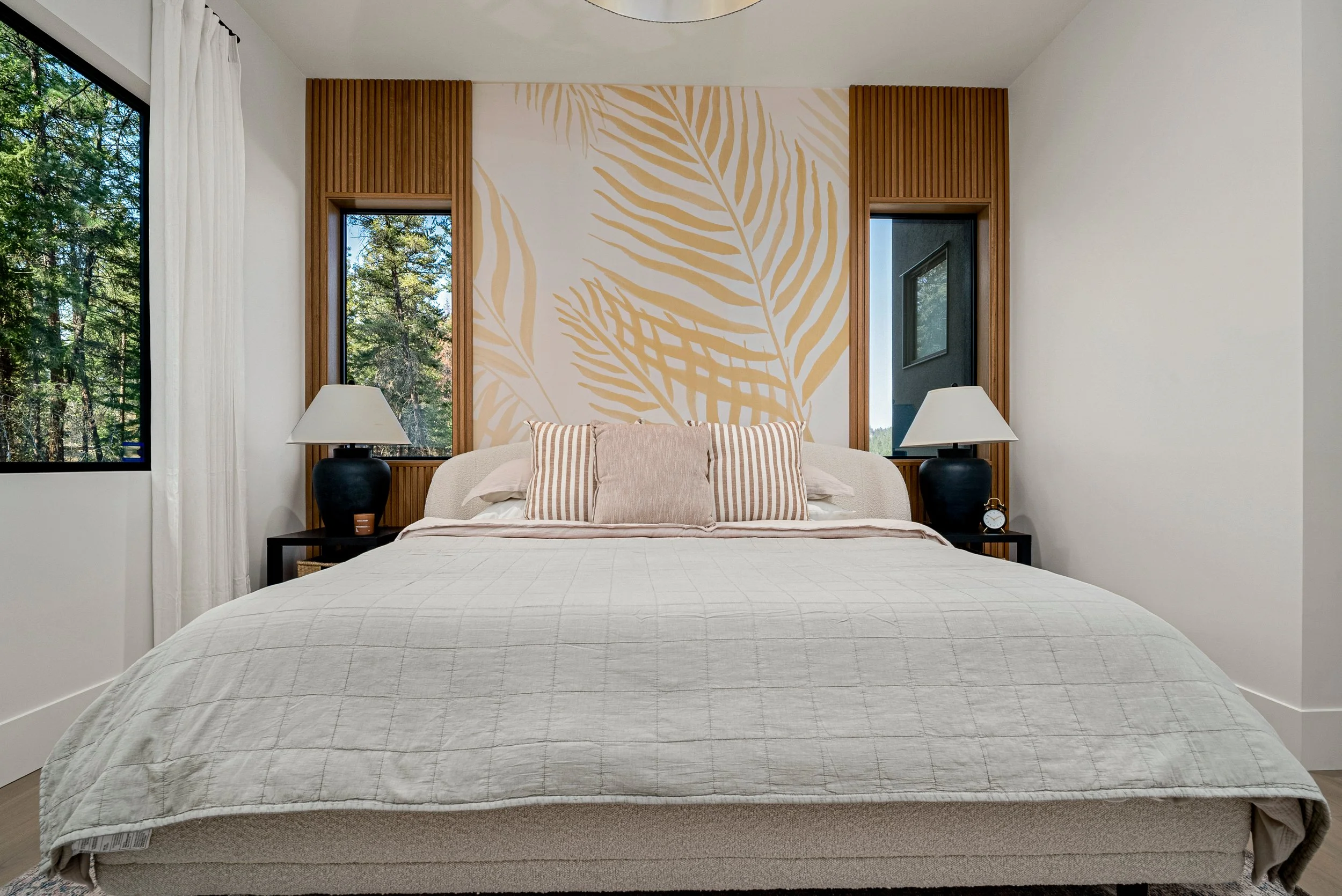 Bedroom at Woodside Showhome with a gold palm-leaf mural, wood slat panels and windows to the forest