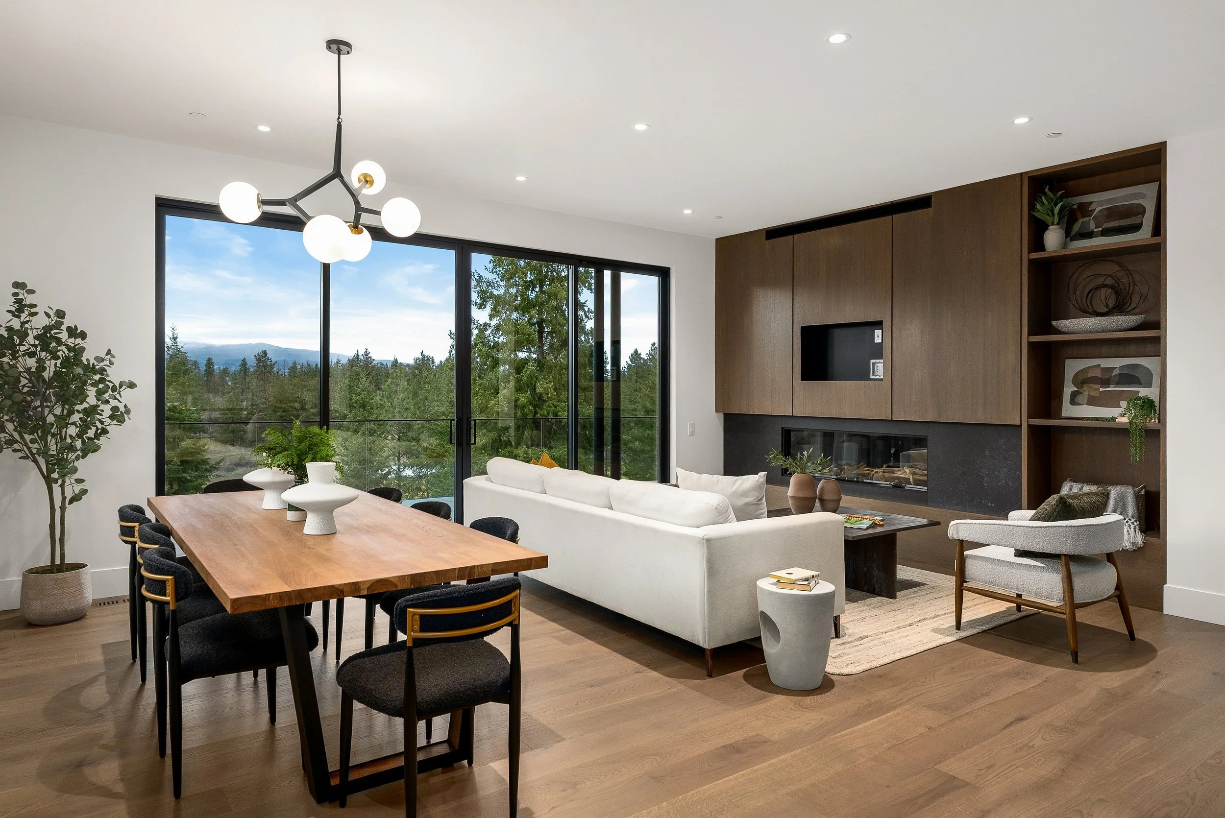 Great room with the dining table, a dark wood media wall and forest views, Terrace House, Predator Ridge