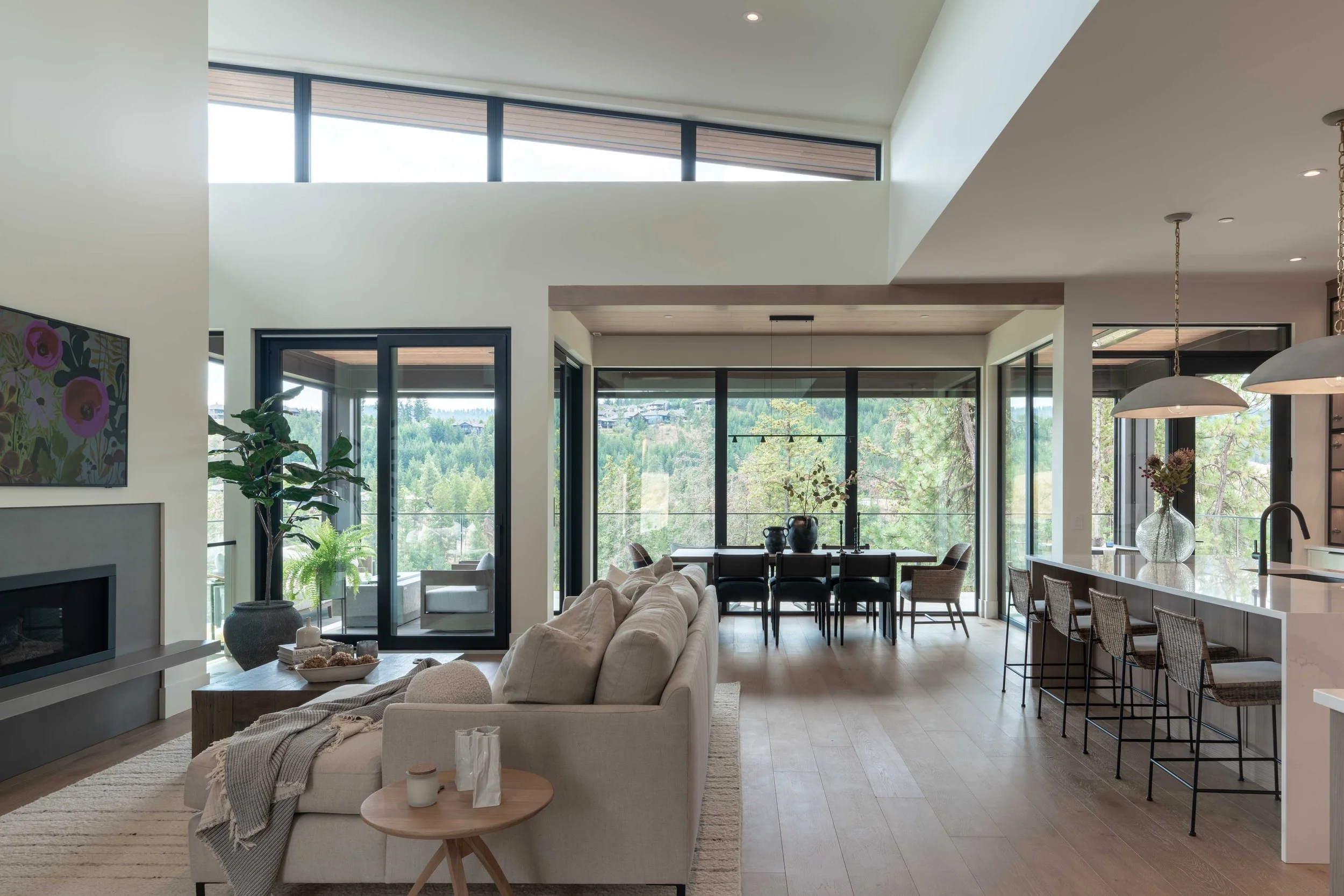 Open great room at Ridge Light House with clerestory windows, a linear fireplace, sofa, dining table and kitchen island