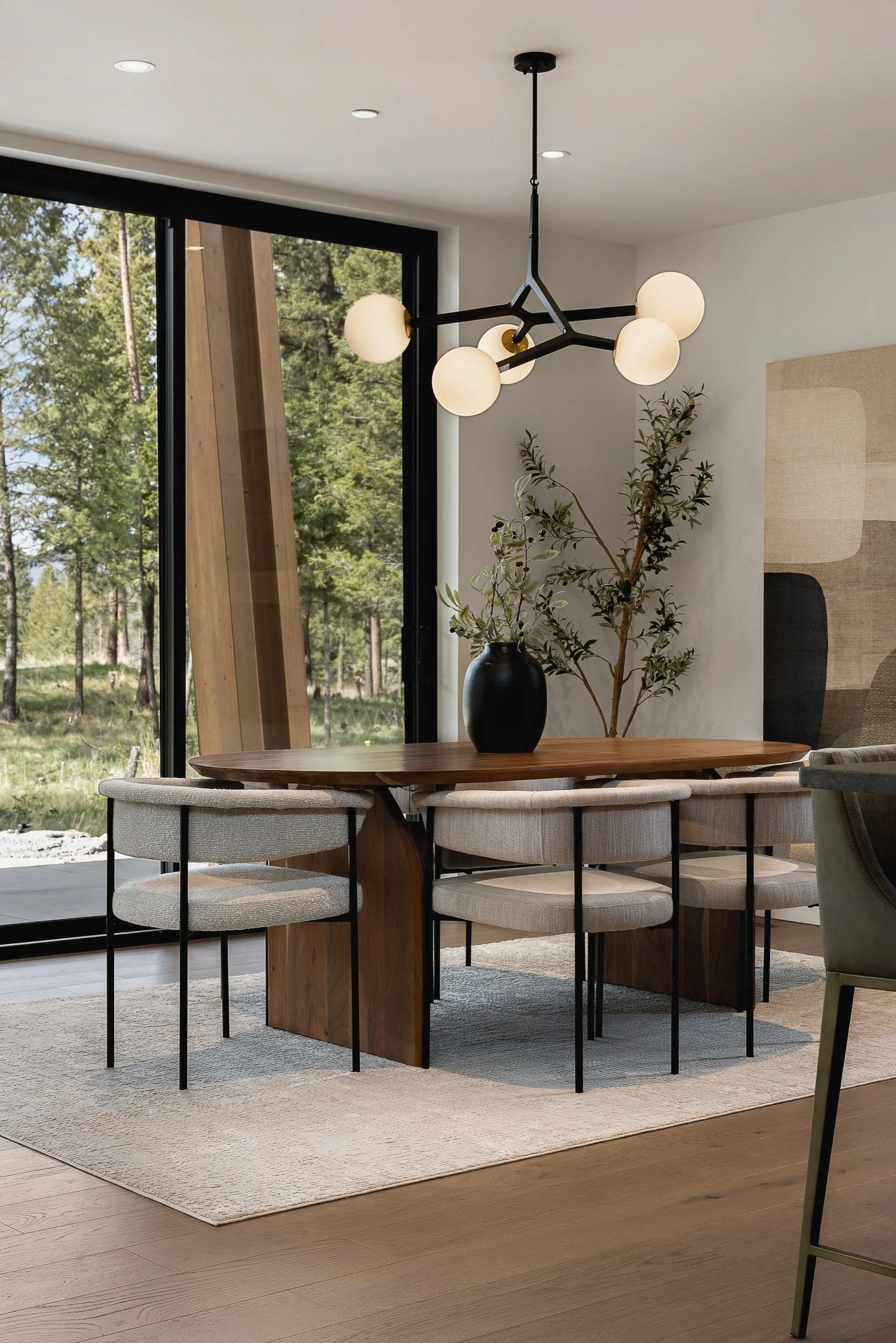 Dining table under a globe chandelier beside the window wall, Green View Residence, Predator Ridge