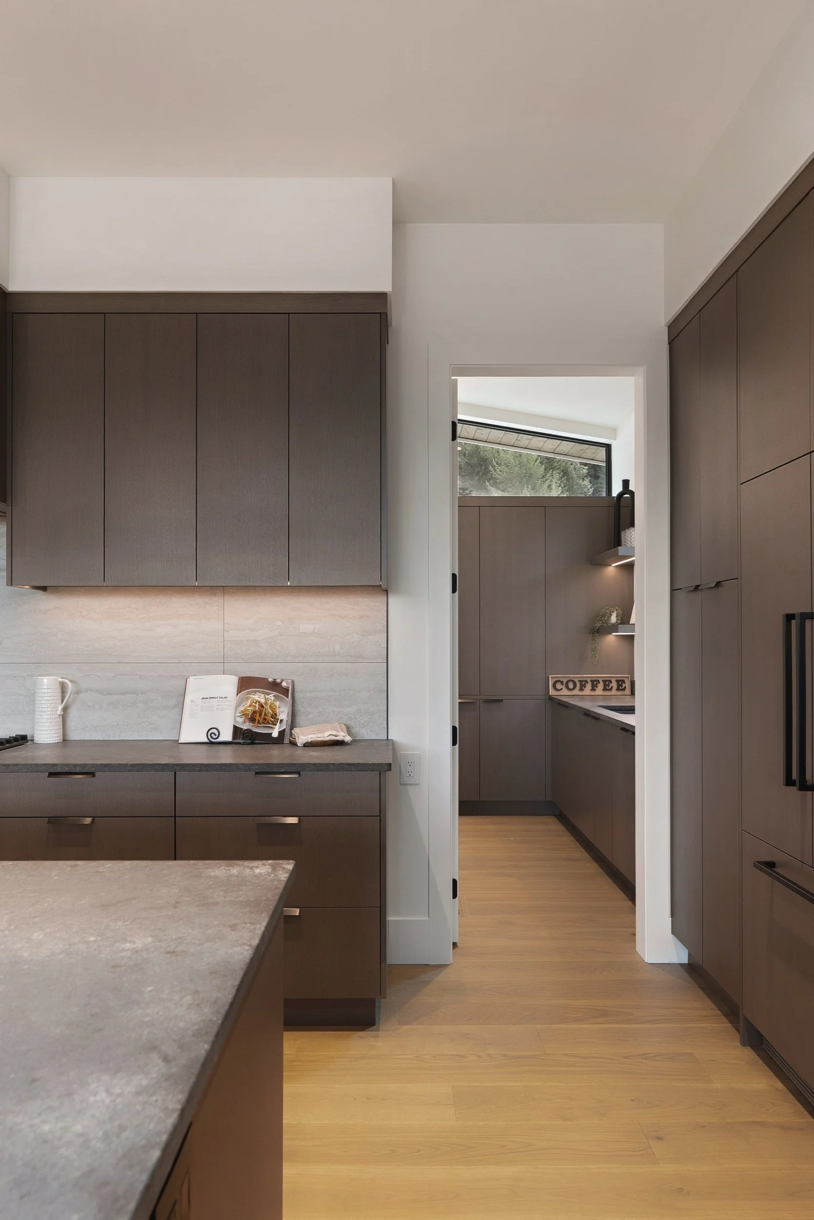 Kitchen wall of dark wood cabinetry with a doorway beyond, Terrace House, Predator Ridge