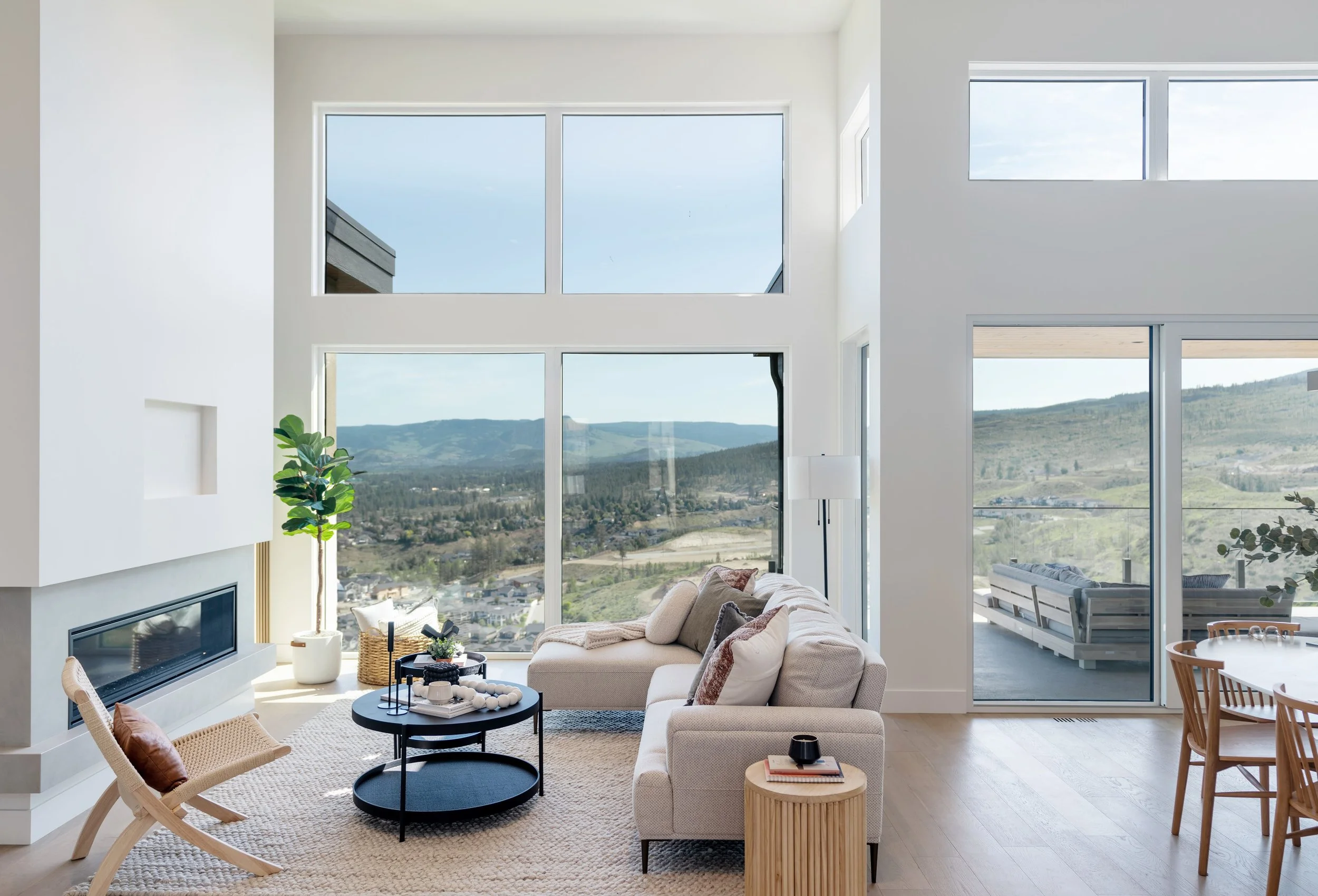 Double-height living room with fireplace and valley-view windows, Trailhead Showhome, Kelowna