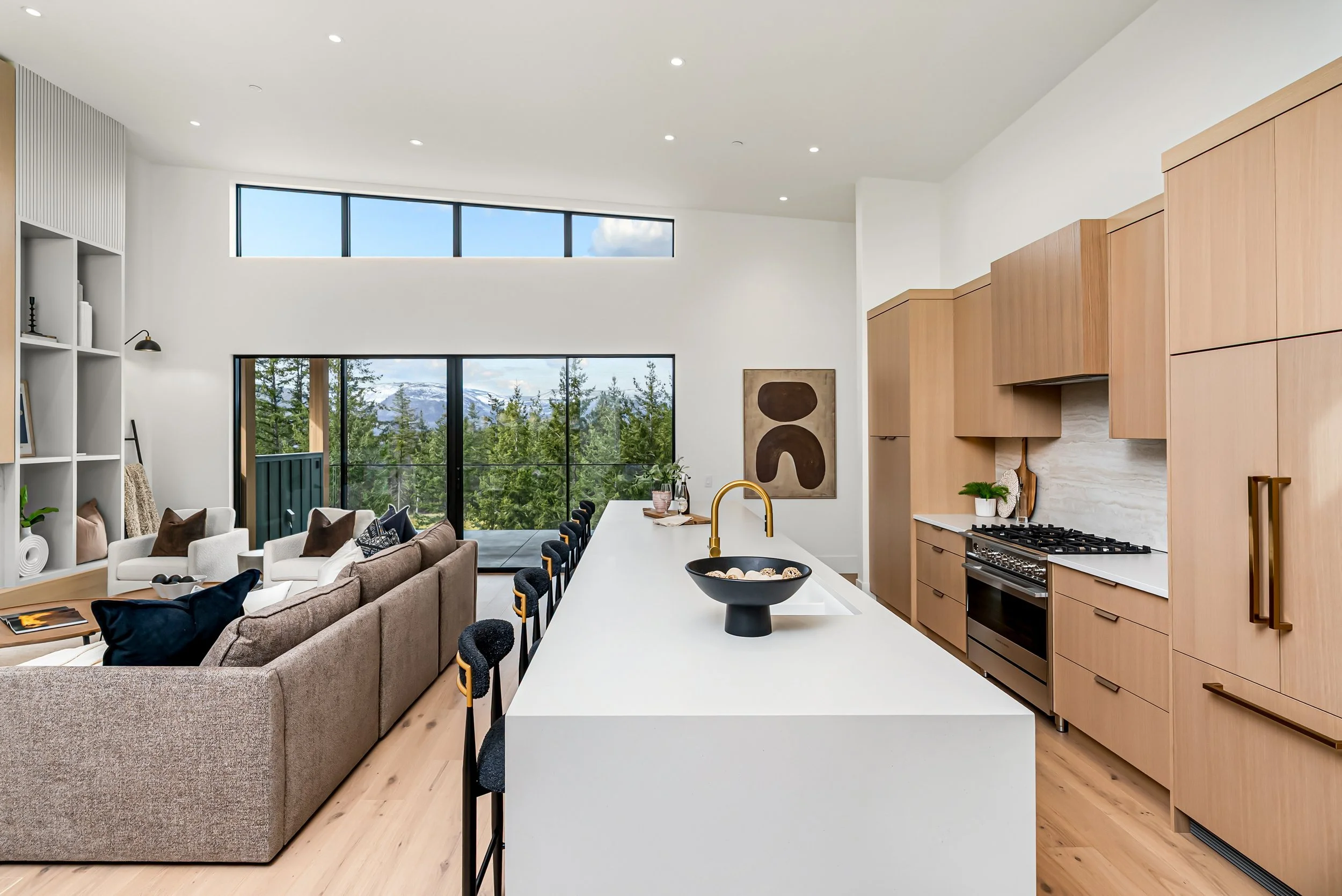 Open kitchen and living area with light oak cabinetry and a long white island, Ellison Walkout, Predator Ridge