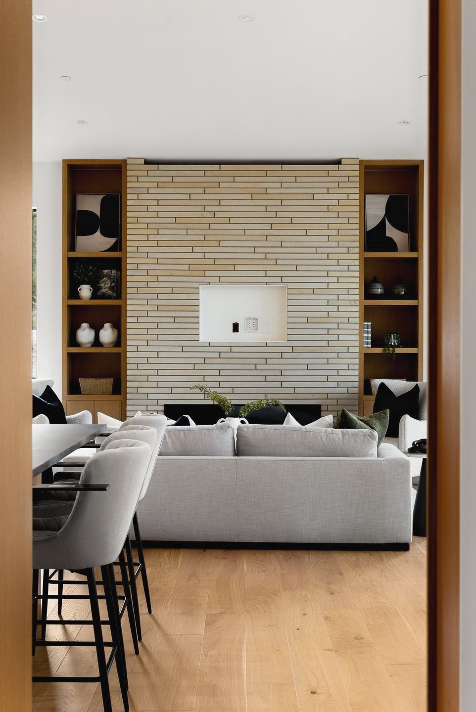 Pale brick fireplace wall with lit oak shelving, seen from the kitchen, Fairway Rancher, Predator Ridge