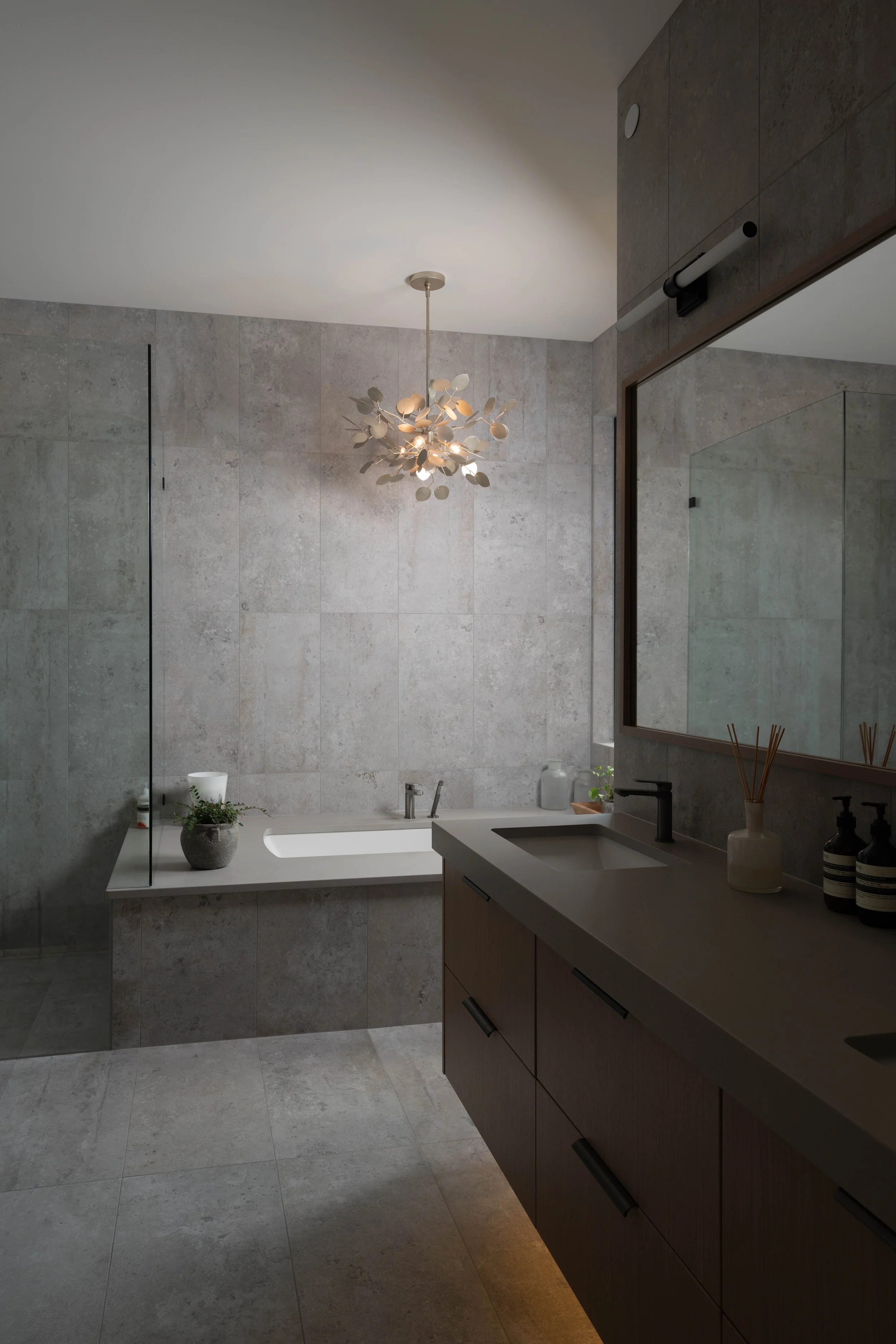 Ridge Light House ensuite with large grey tile, a soaker tub, floating dark wood vanity and sculptural chandelier
