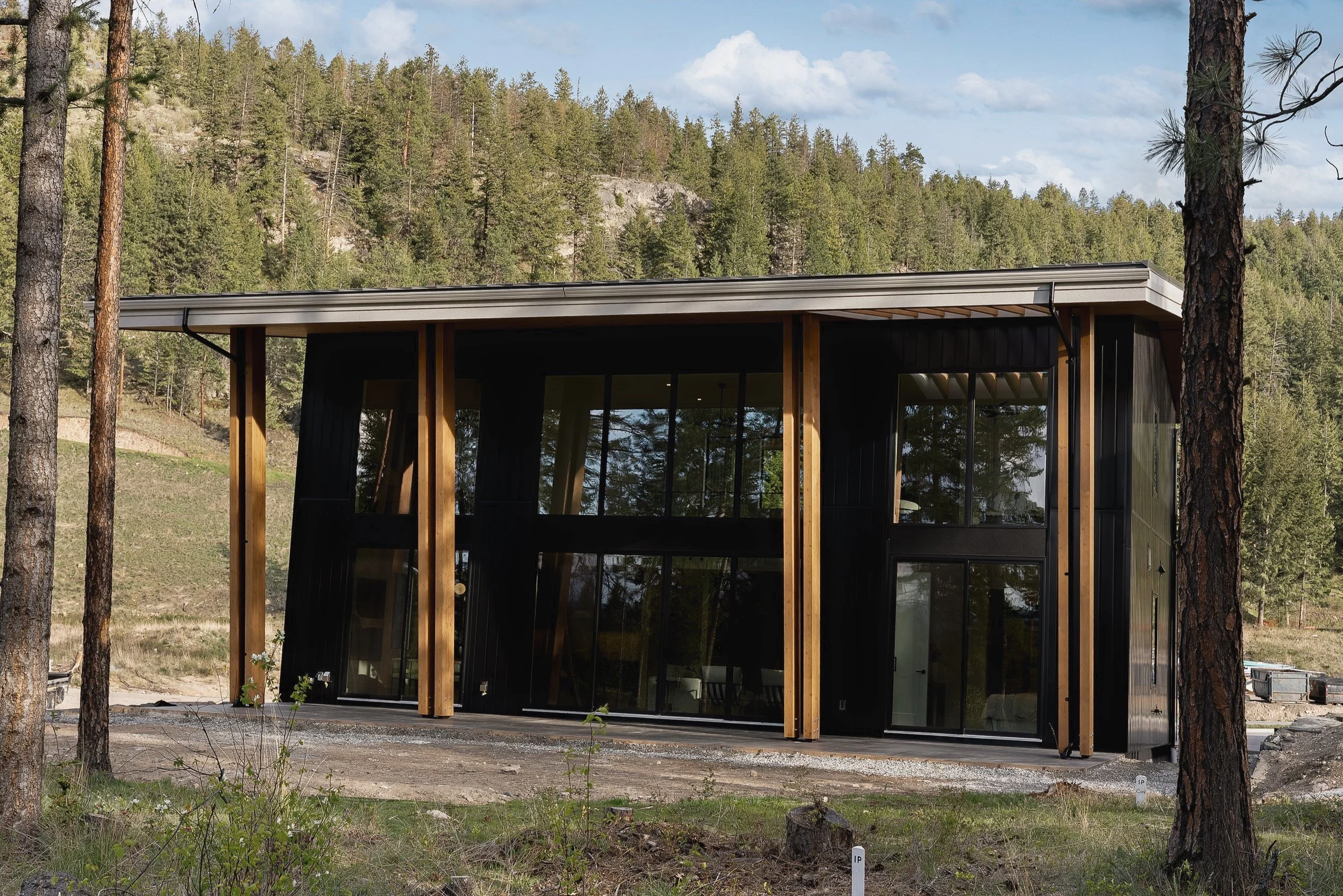 Rear exterior with double-height glass and timber posts, Green View Residence, Predator Ridge