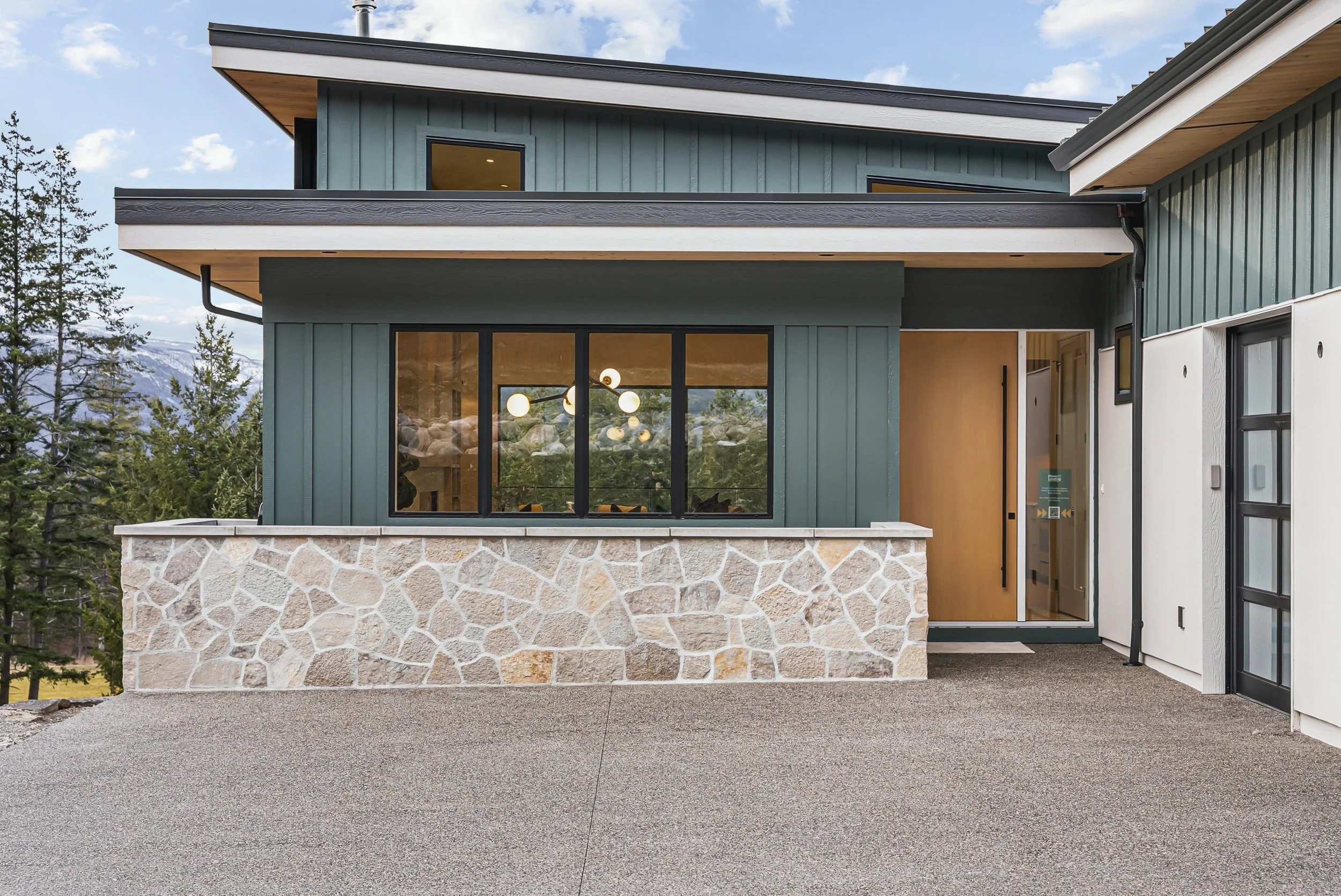 Front entry with green vertical siding and a stone base, Ellison Walkout, Predator Ridge