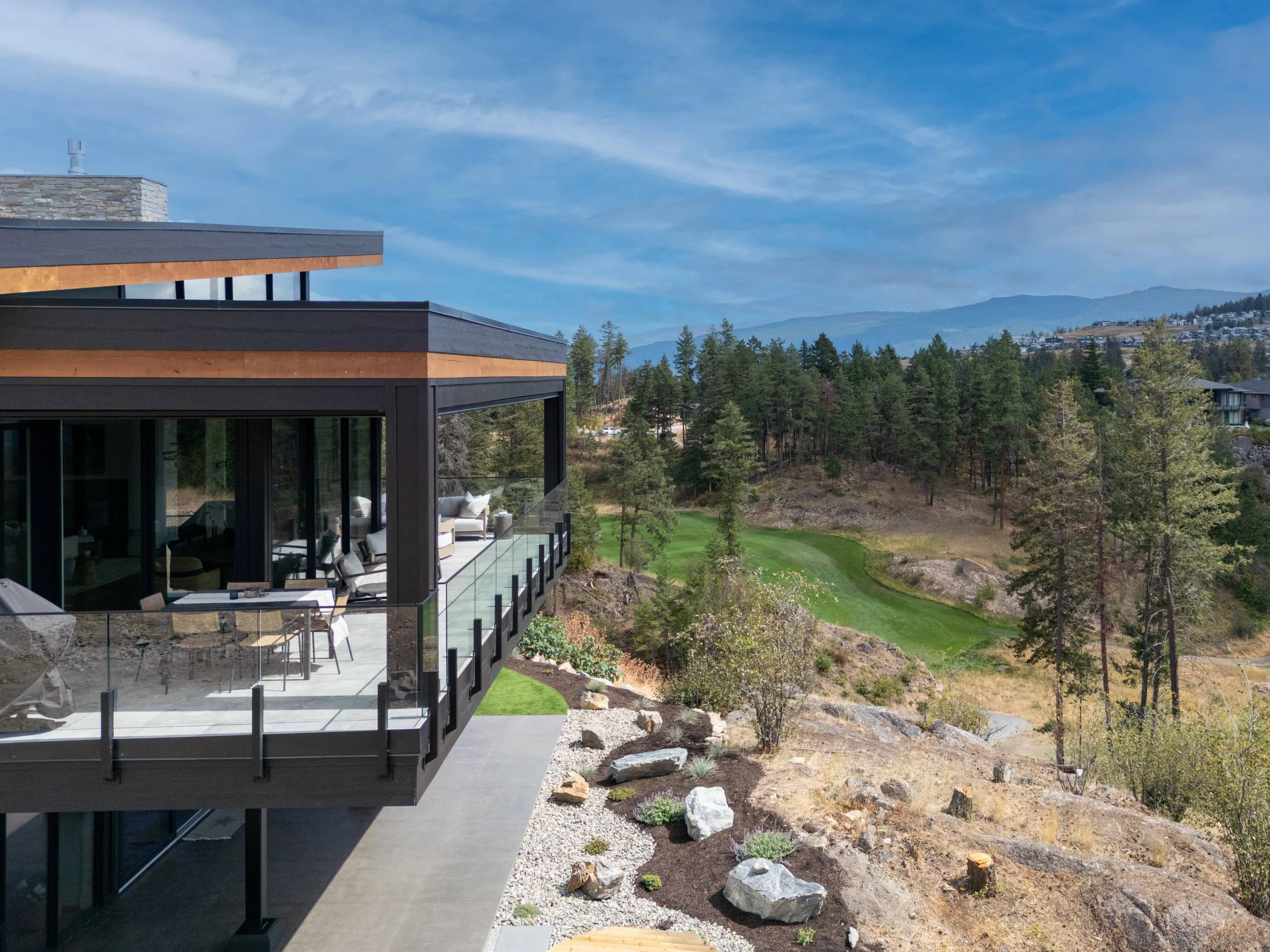 Covered deck with glass railing at Ridge Light House, overlooking a fairway and pine forest at Predator Ridge