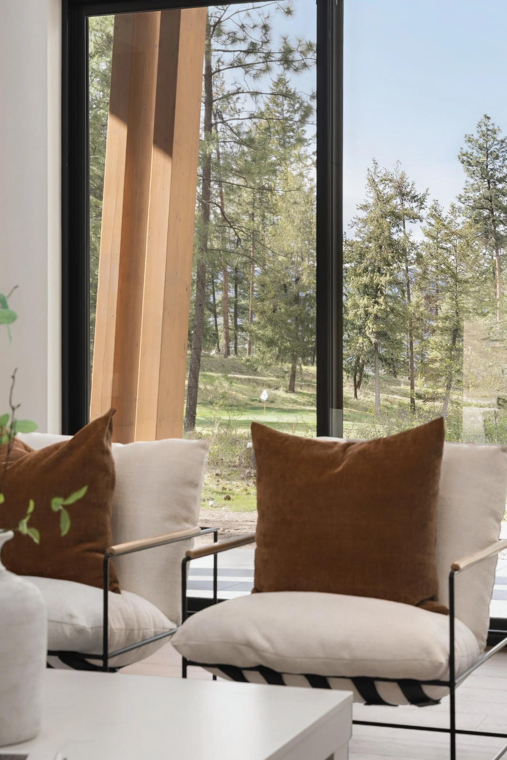 Lounge chairs by the window wall, with a timber post and the fairway beyond, Green View Residence, Predator Ridge