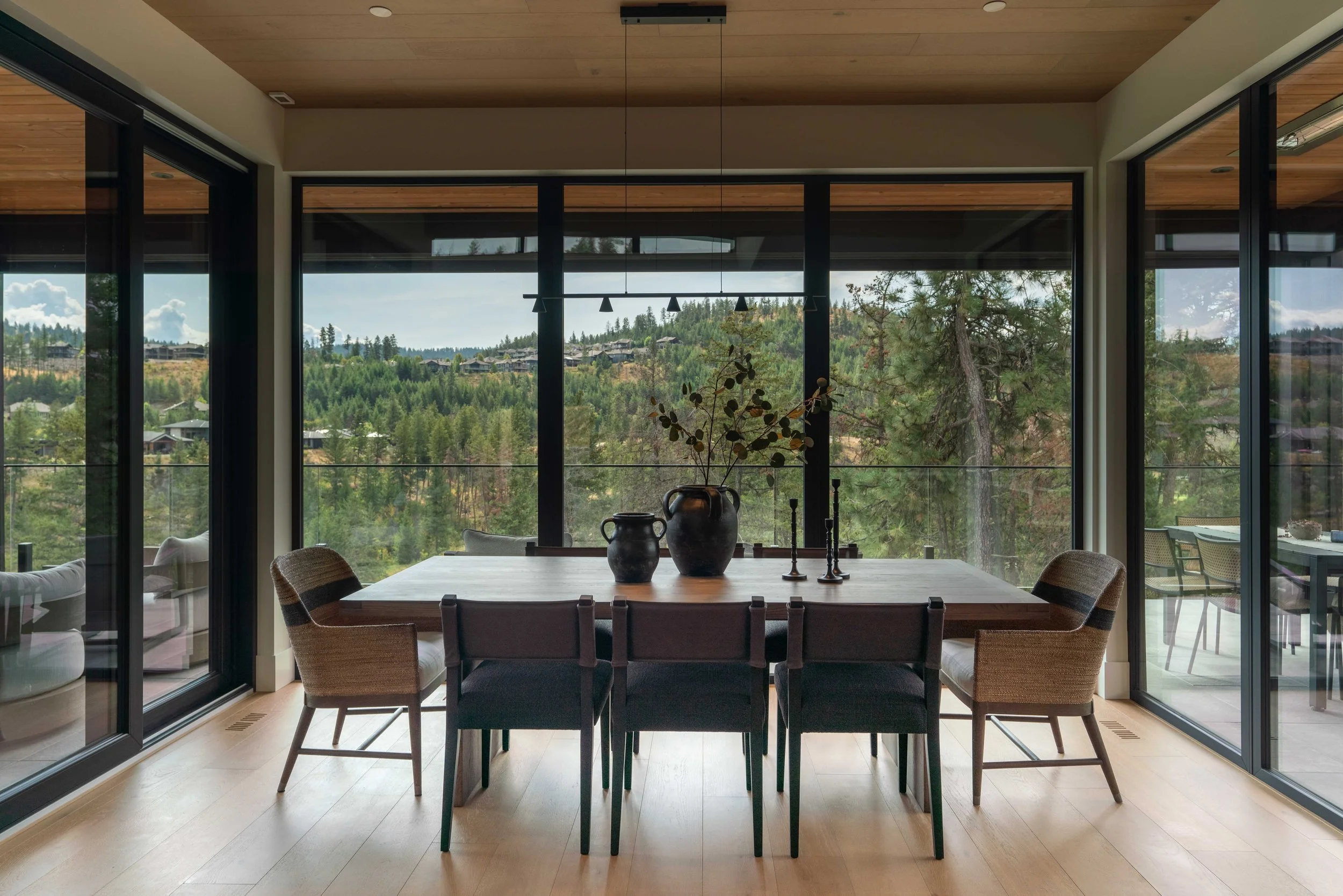 Dining room at Ridge Light House with a wood ceiling, long table and floor-to-ceiling windows to the treed hillside