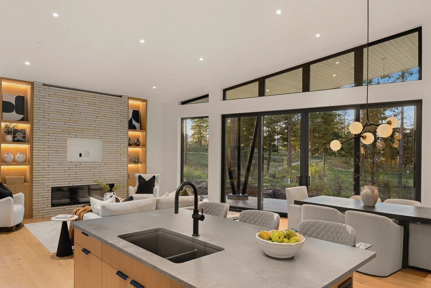 Kitchen island with a grey stone-look top, looking to the fireplace and the glass wall, Fairway Rancher, Predator Ridge