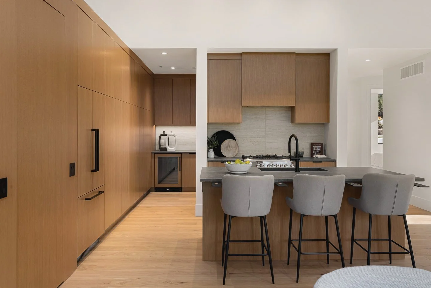 Full-height oak cabinet wall and kitchen island with grey stools, Fairway Rancher, Predator Ridge