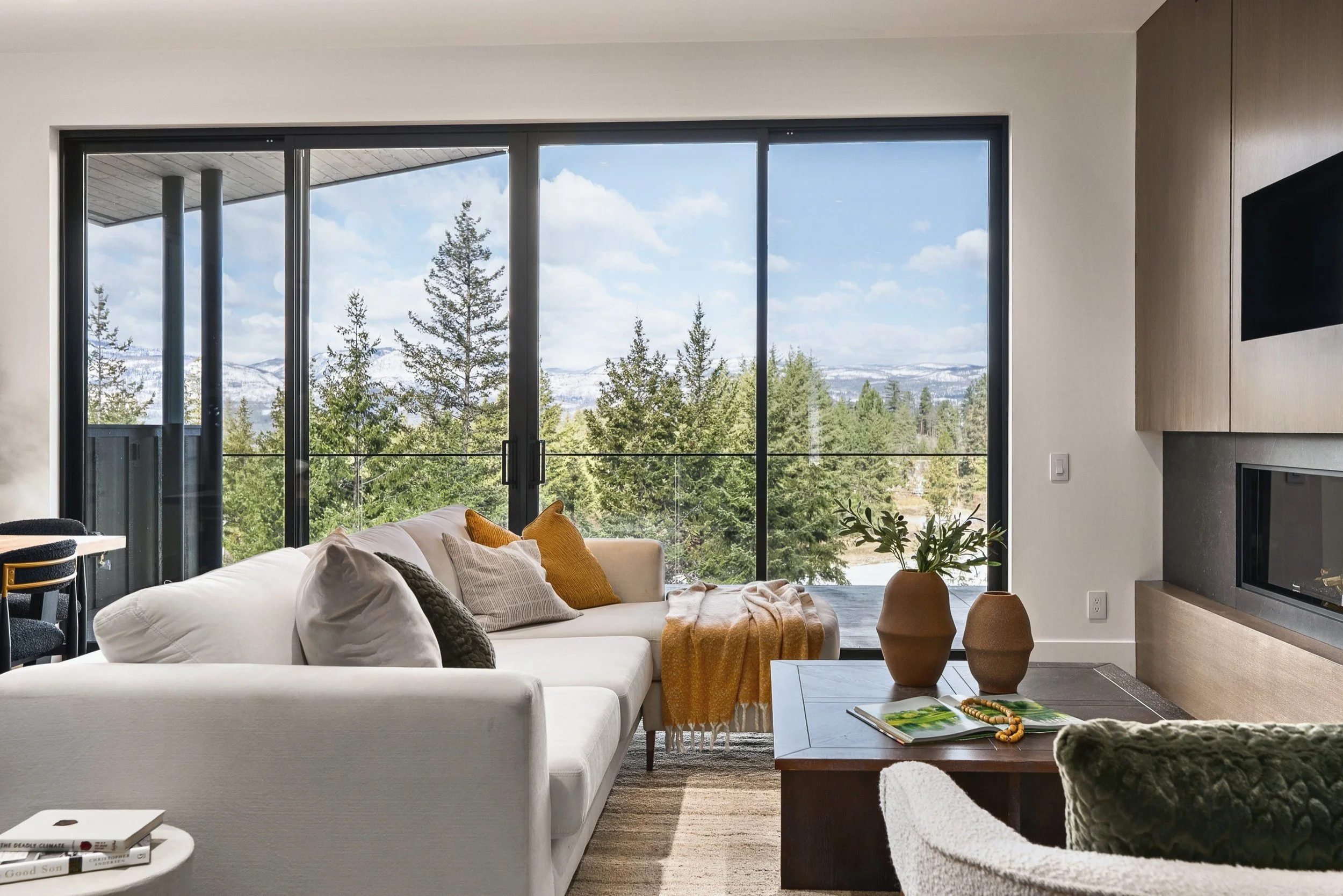 Living area facing a wall of glass to the trees and mountains, Terrace House, Predator Ridge