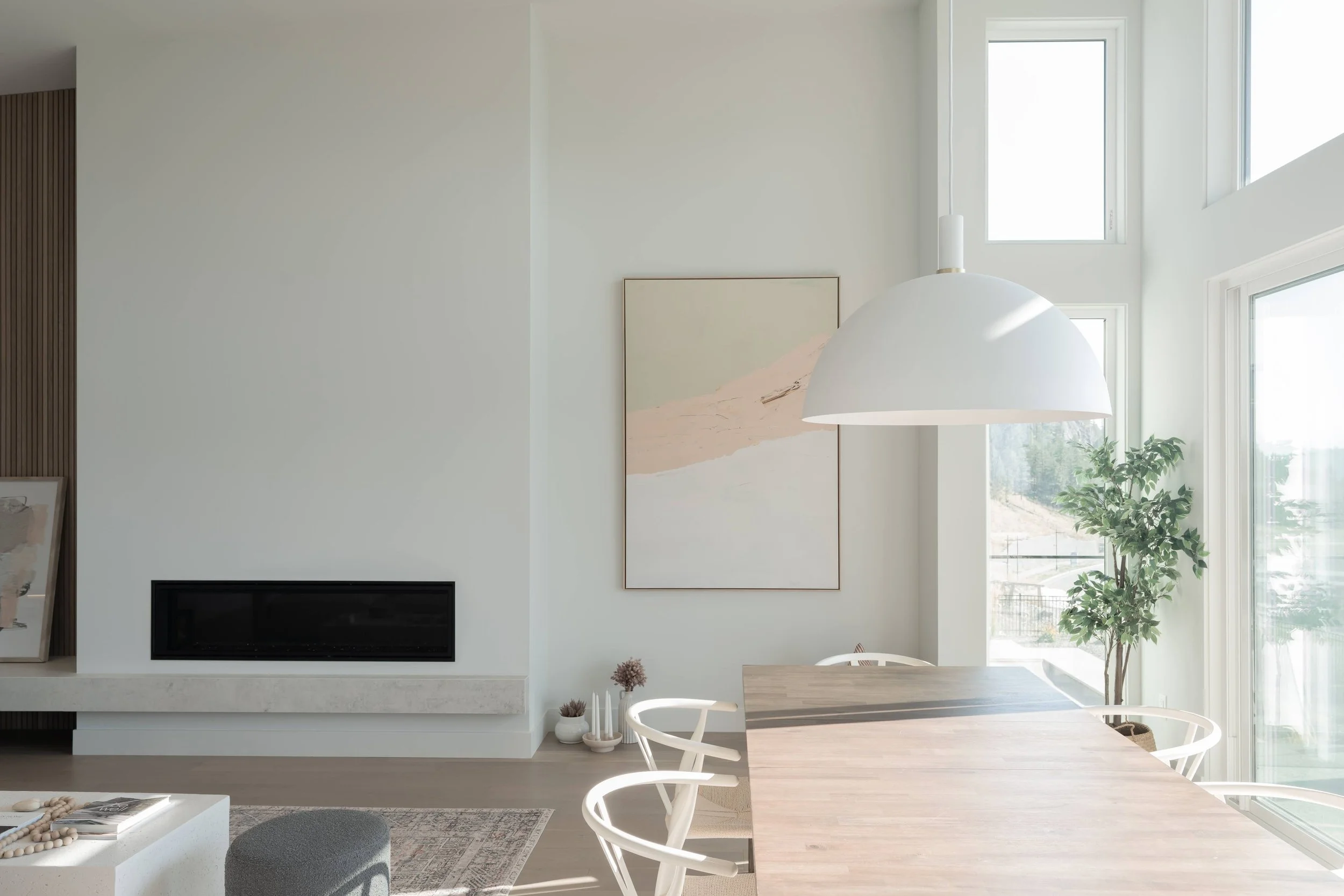 Dining area with a white pendant light beside a minimalist linear fireplace, Lakestone Showhome, Lake Country