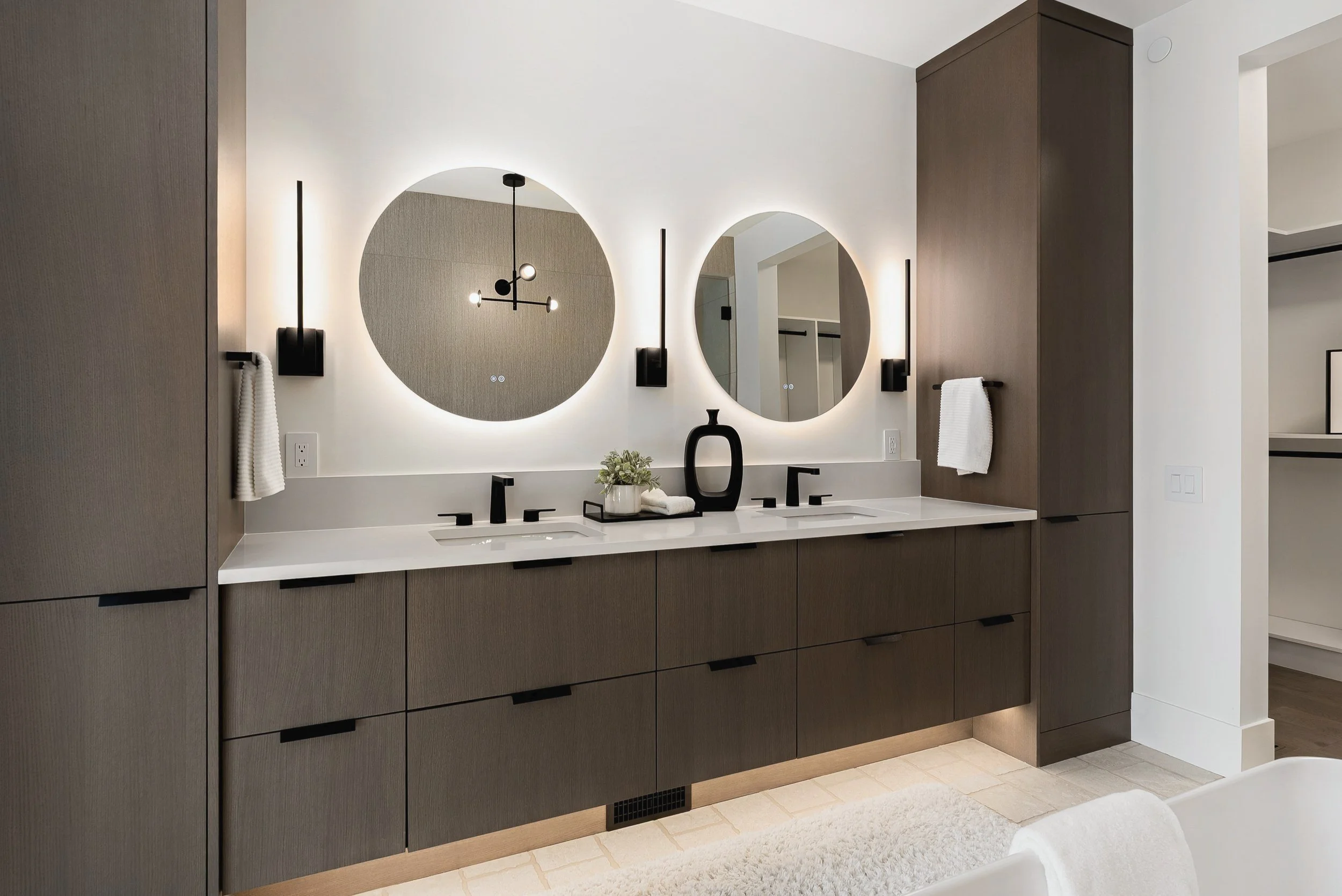Double vanity with dark oak cabinetry and round backlit mirrors, Green View Residence, Predator Ridge