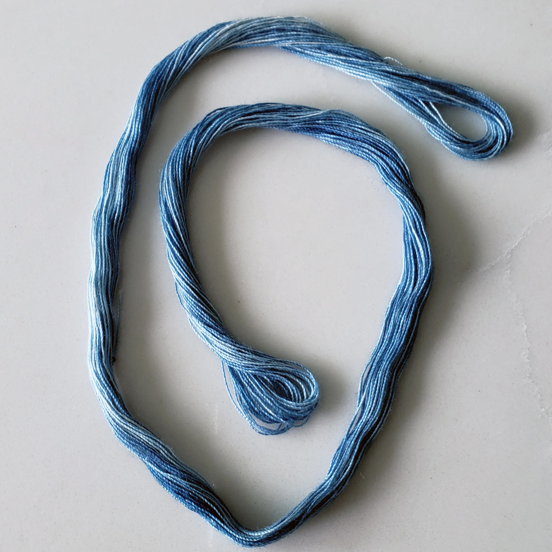 Hand-dyed indigo D-Core cotton thread skein in a medium blue shade for hand embroidery, sashiko stitching, and textile mending.