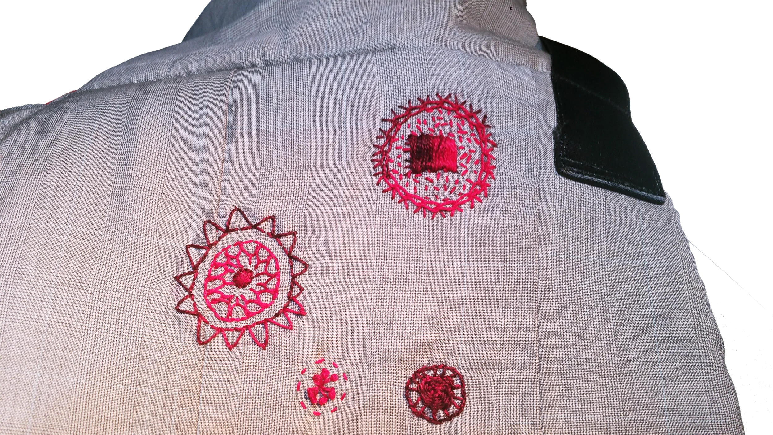Close-up view of the back of a grey wool suit bag featuring custom red visible mending and circular embroidery stitches over moth holes.