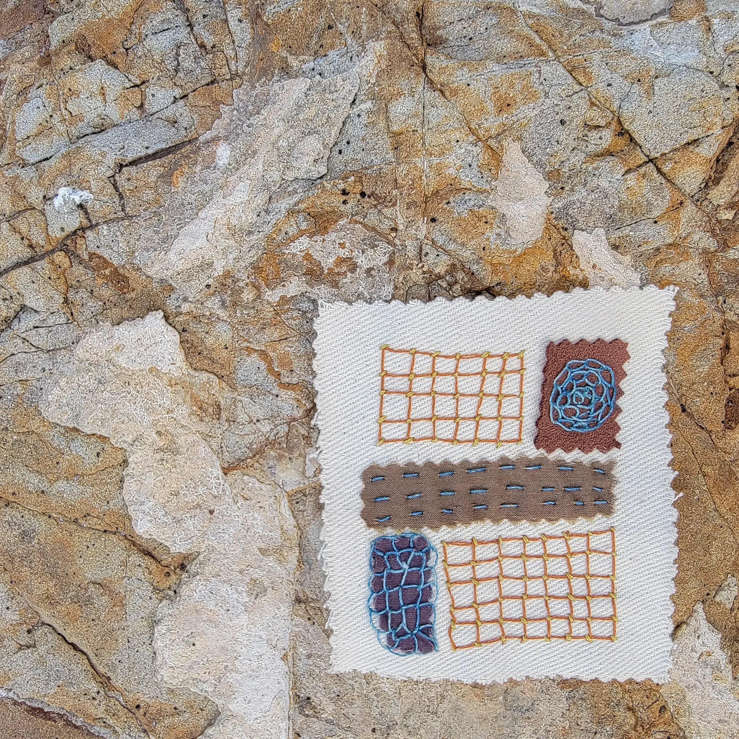 Hand-Stitched Sampler Patch: Patches travel with me — this one was stitched somewhere in Texas, and the rust, clay, and stone tones I was surrounded by clearly worked their way into the thread. A woven grid in mustard, a darned circle in blush and bl