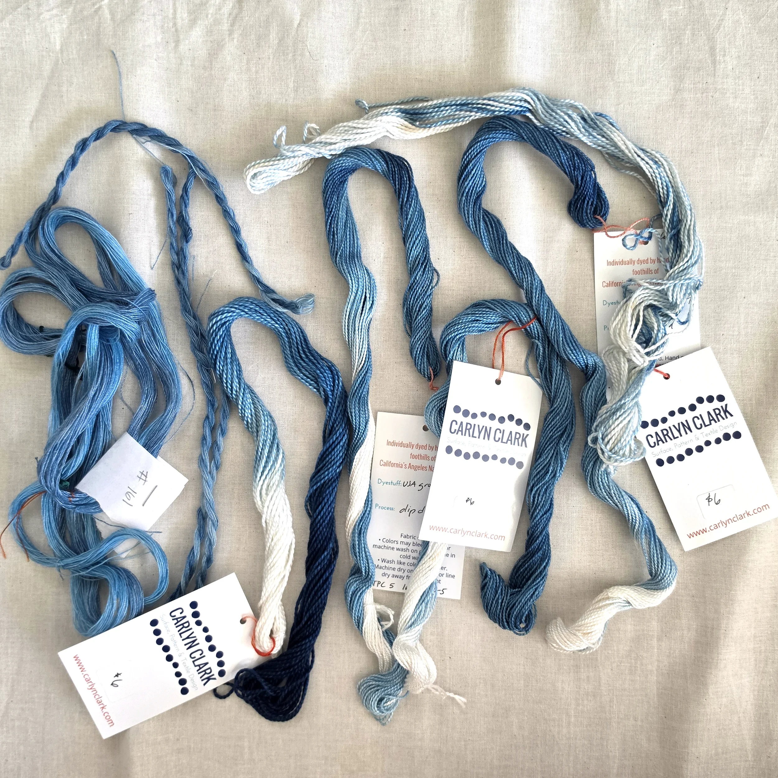 Hand-dyed indigo threads in several shades of blue, twisted into loops with Carlyn Clark tags.