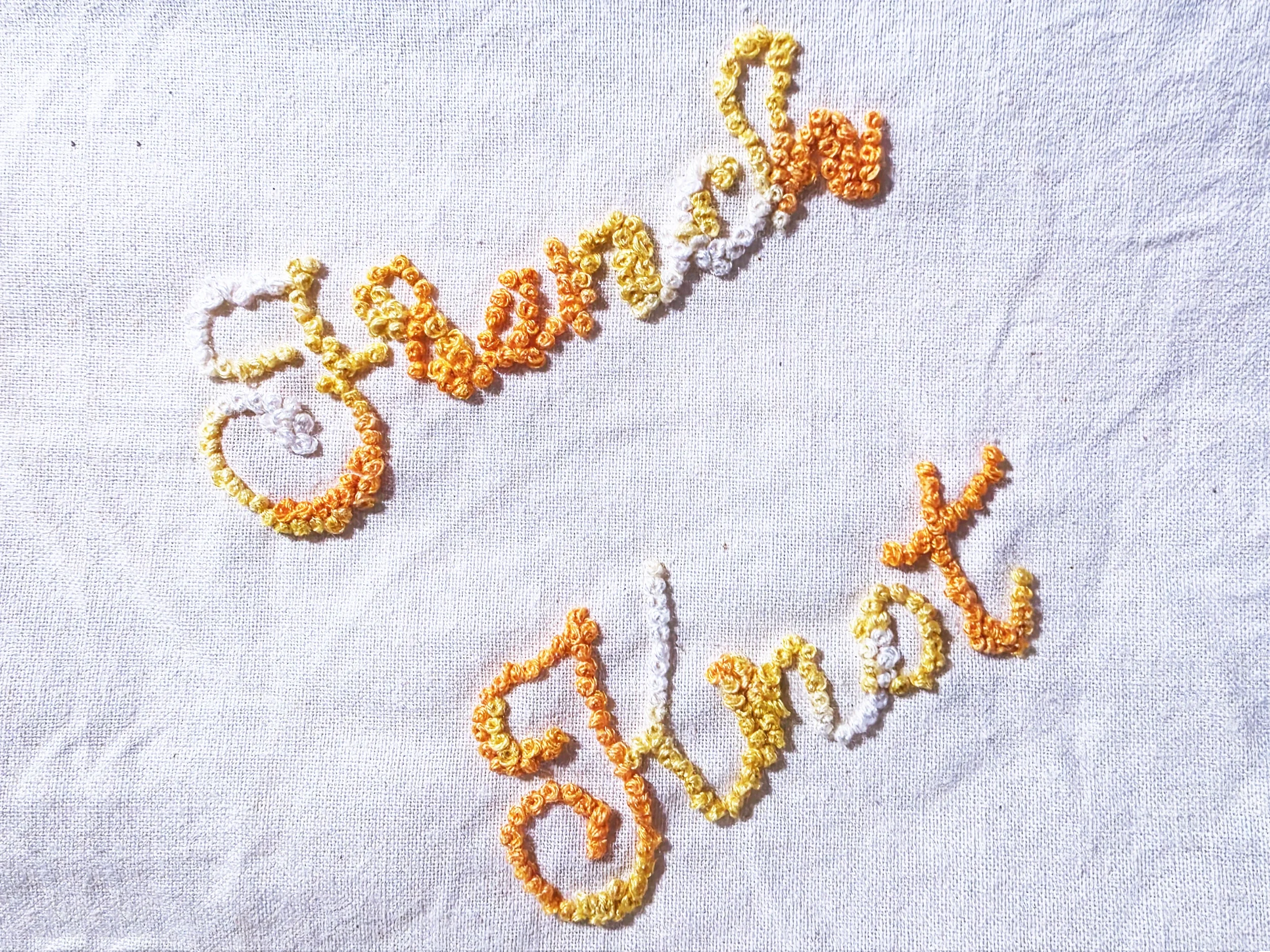 Hand-stitched cursive lettering spelling French Knot using warm yellow and orange embroidered French knot stitches on neutral fabric.