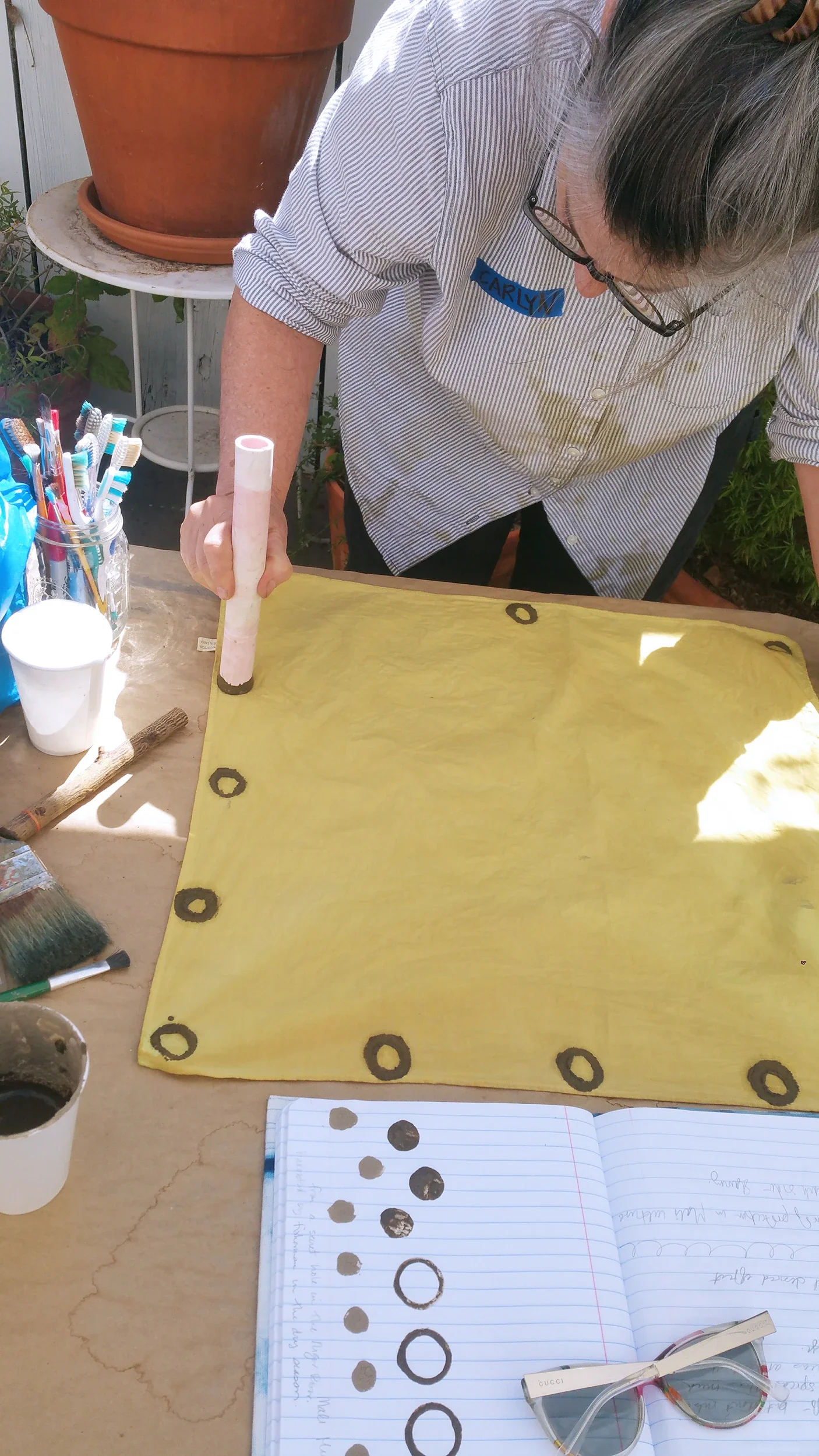 Carlyn Clark hand-printing custom surface patterns using Malian tannin-rich mud on plant-dyed fabric during a textile workshop.
