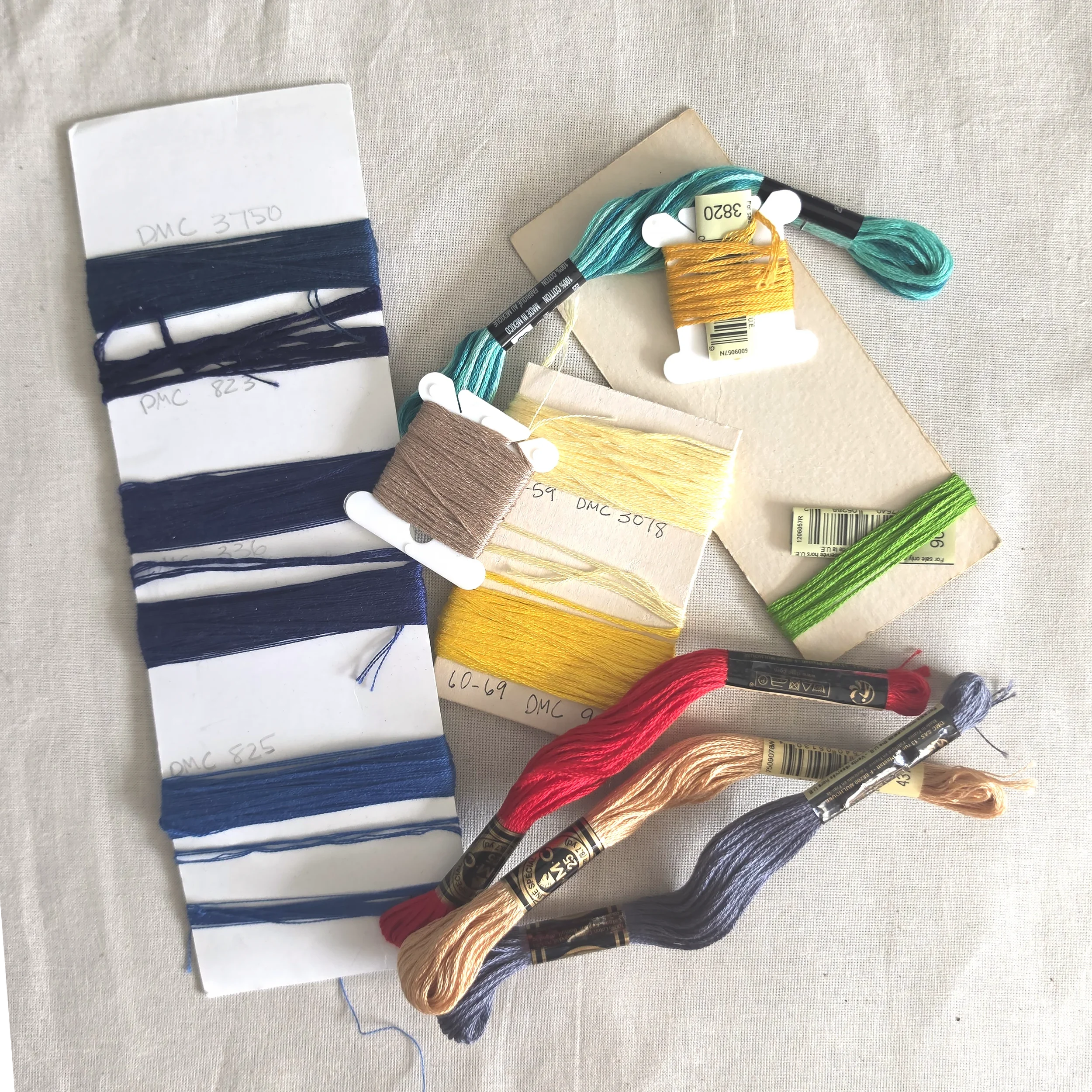DMC 6-strand embroidery floss in skeins and wound on cards and bobbins, with a card of navy thread.