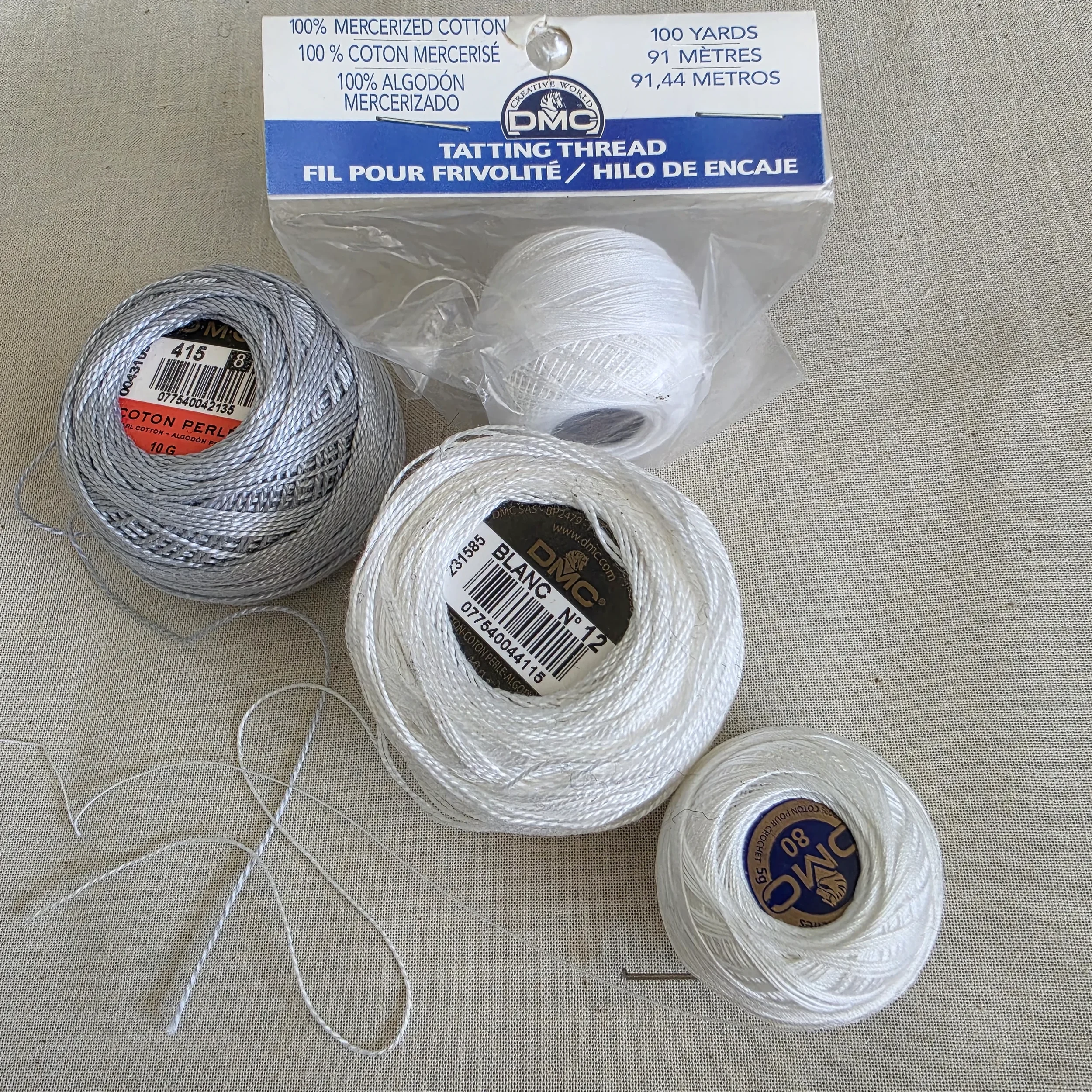 Balls of DMC size 8 and 12 pearl cotton and tatting thread, showing the difference in thickness.