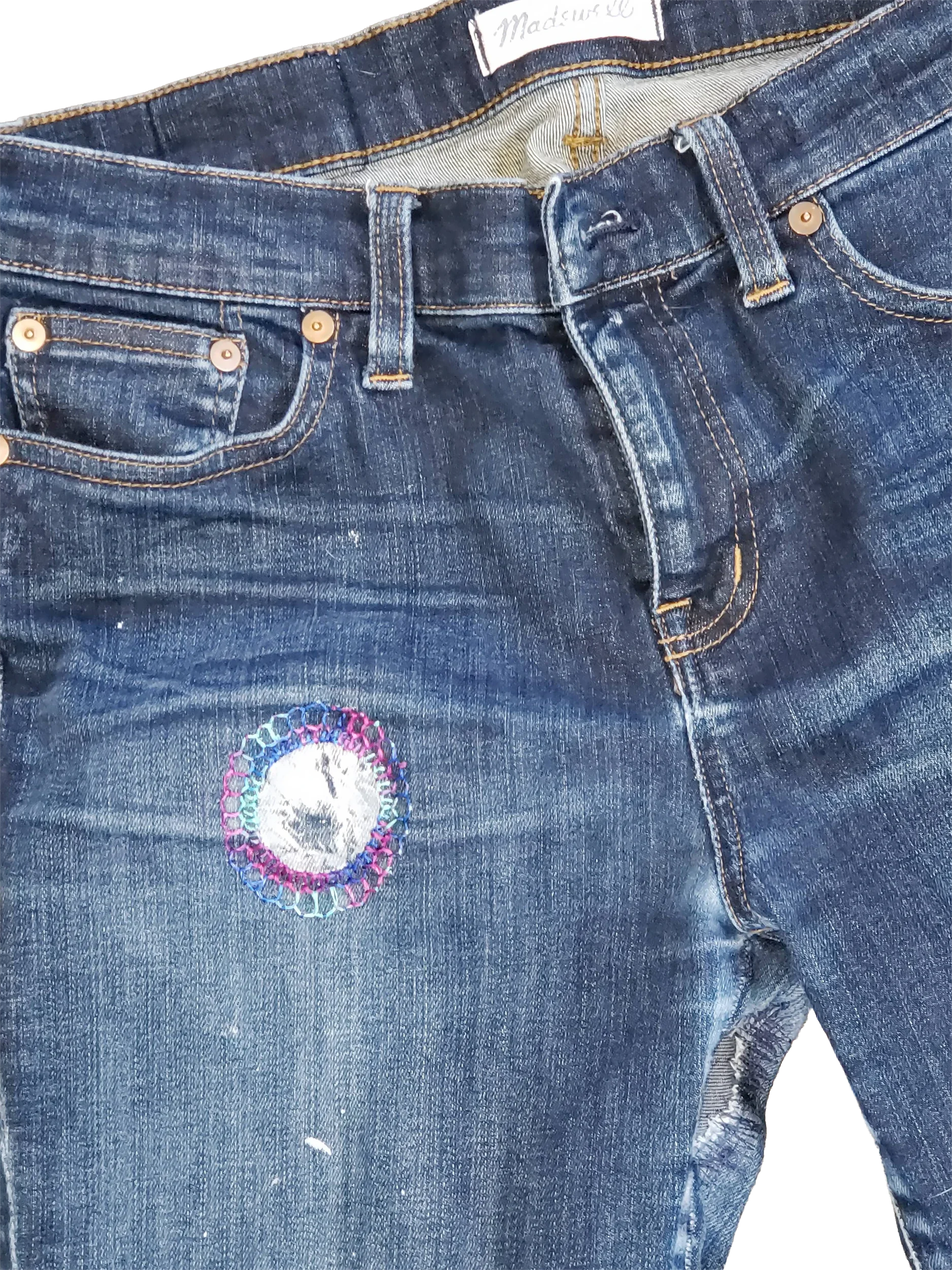 Dark-wash Madewell denim featuring custom visible mending on the upper thigh, saddle, and inseam. The focal point highlights a circular textile patch framed by concentric hand stitching in vibrant pink, purple, and cyan thread. Reinforced with durabl