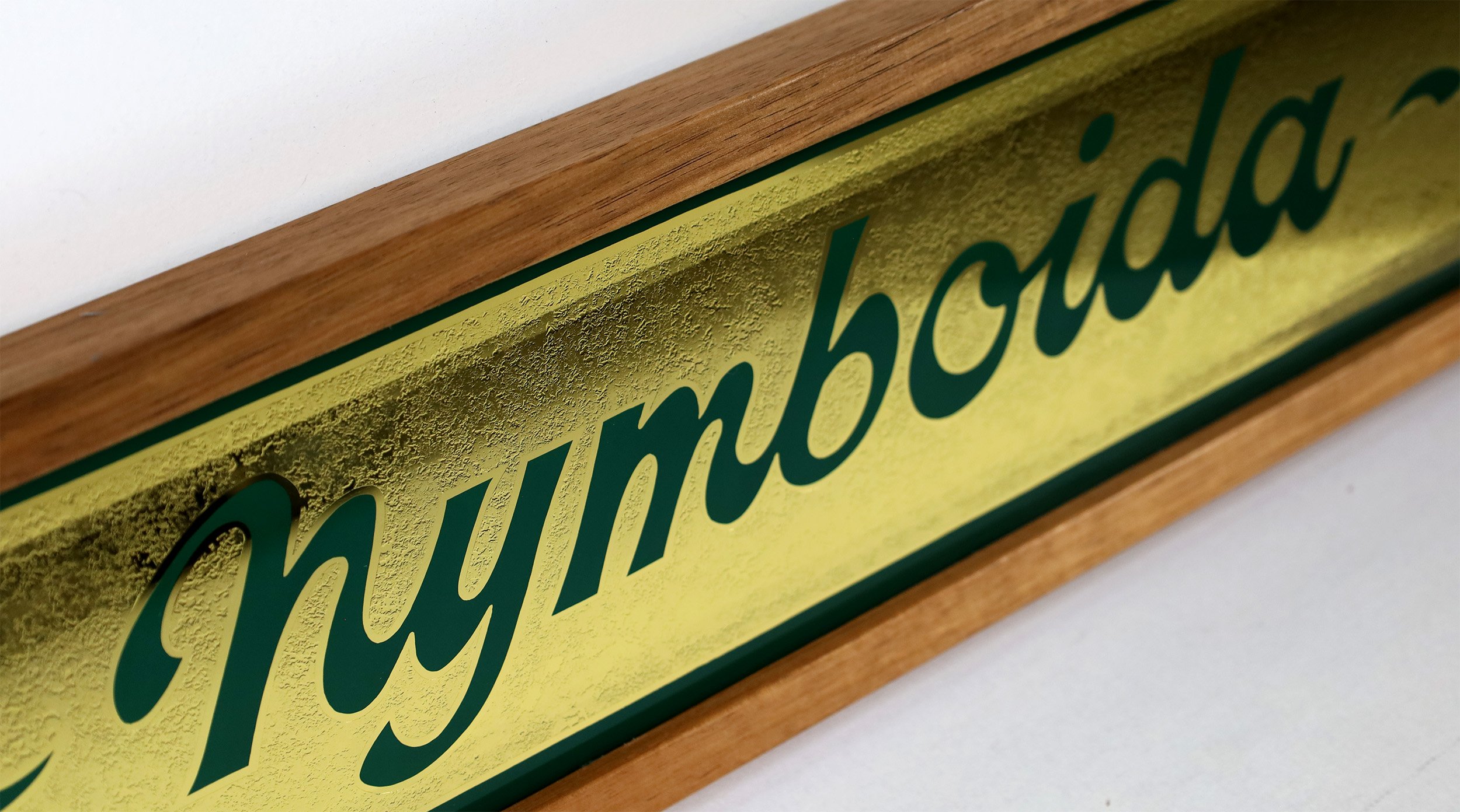 Green script lettering with acid etched gold background and green enamel border