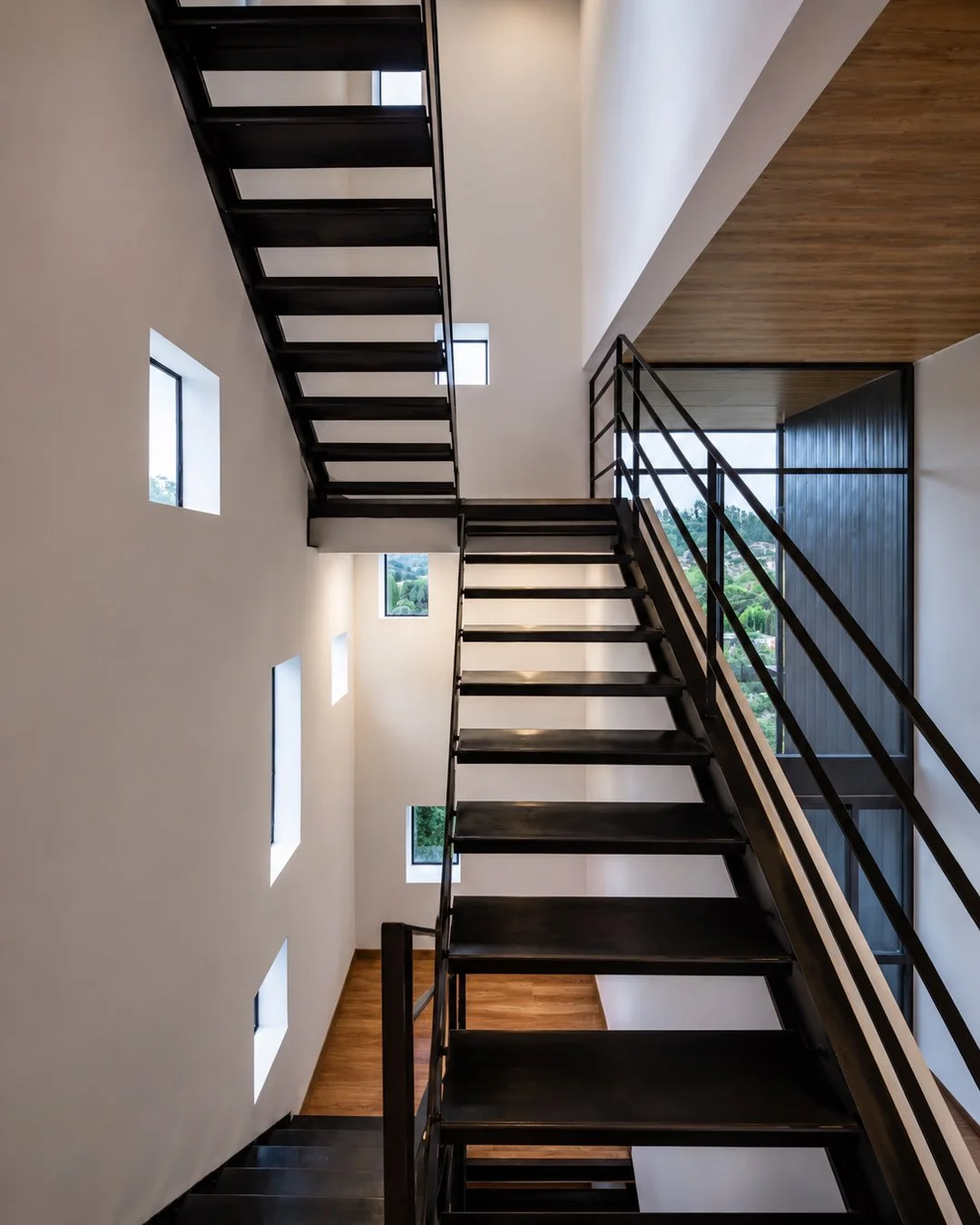 Escalera interior de una de las tres viviendas independientes de Pillagua Barranco, con estructura metálica negra, doble altura y entradas de luz natural. Proyecto diseñado por ENDARA ARQUITECTOS en Cumbayá.
