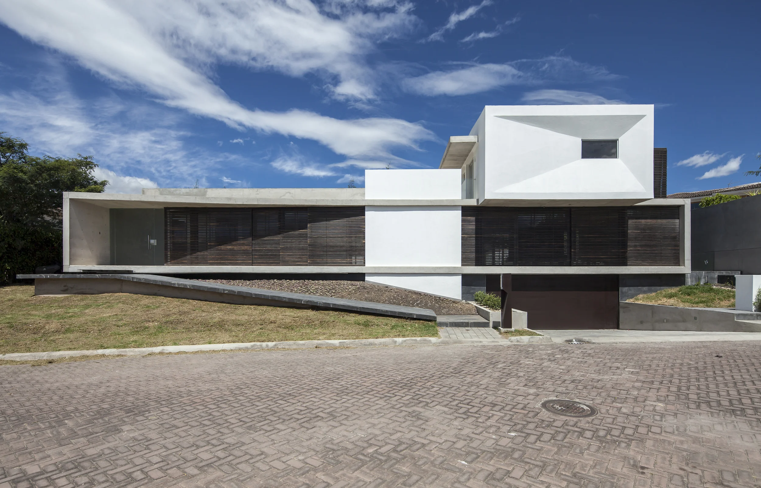 Casa L6, Fachada frontal moderna, contemporánea, con hormigón visto, madera y vidrio. Diseñada por Endara Arquitectos