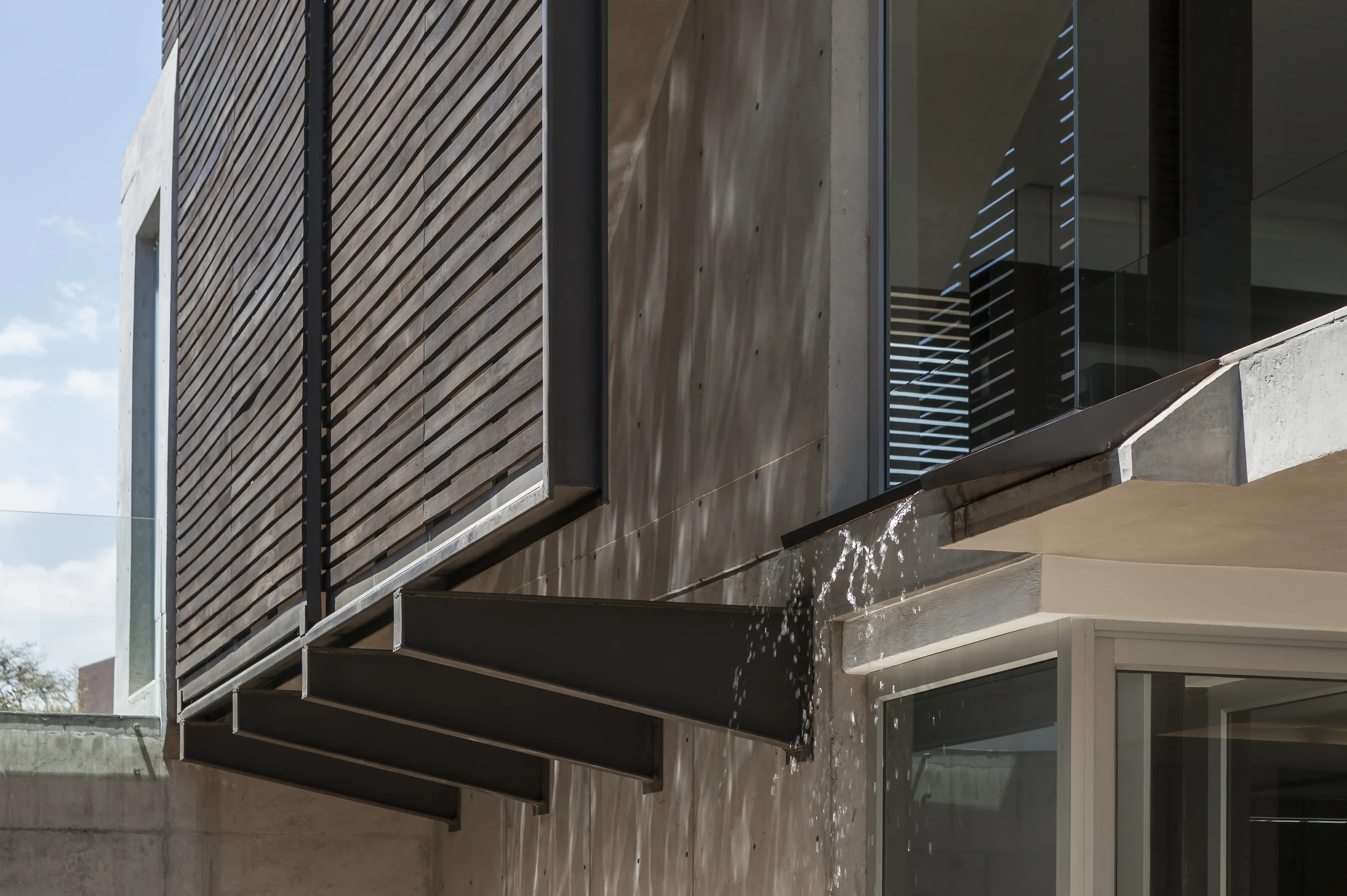 Casa L6, Fachada lateral con celosías y caída de agua decorativa. Diseñada por Endara Arquitectos.