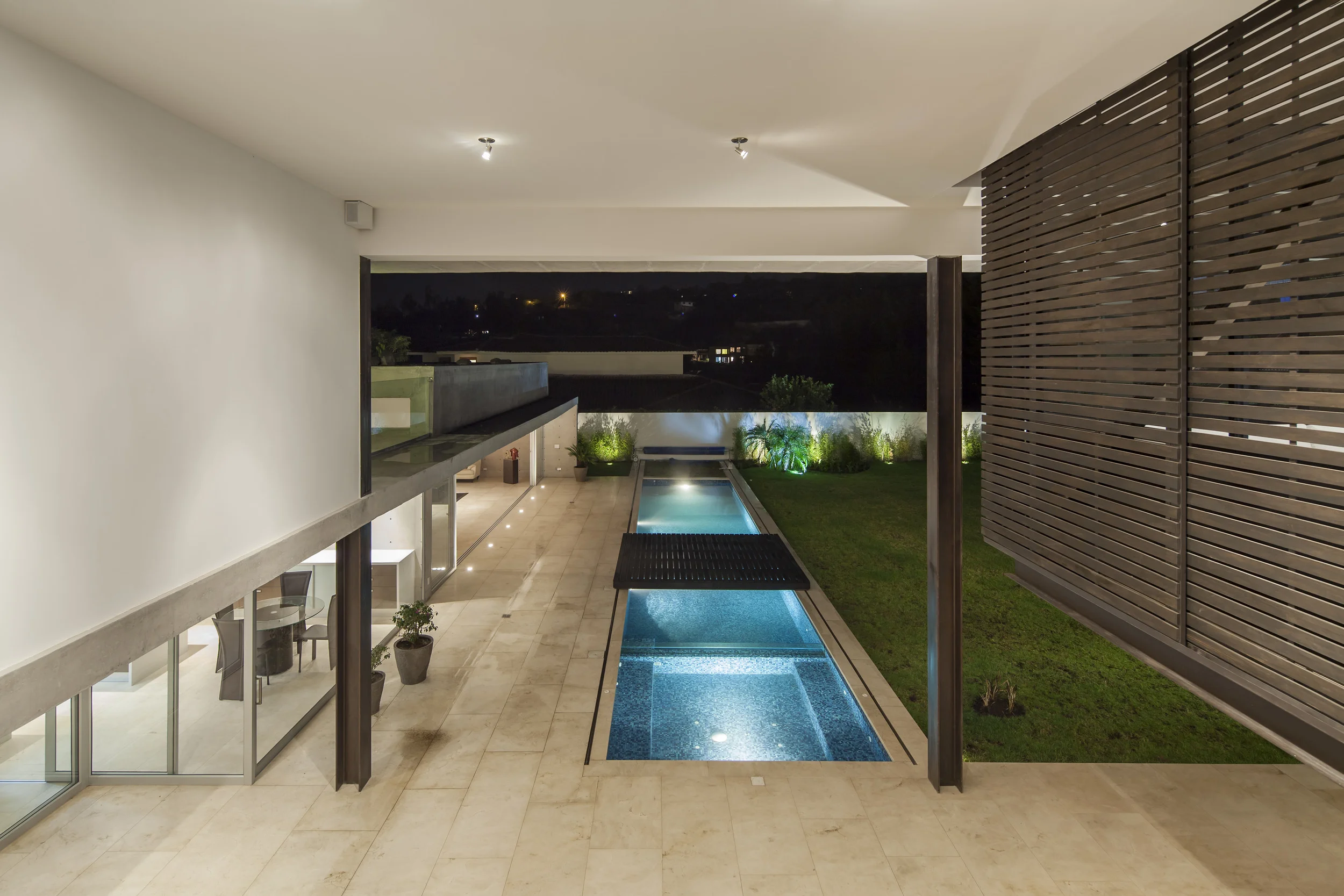 Casa L6, Vista desde pasillo de vidrio hacia la piscina y porche. Diseñado por Endara Arquitectos.