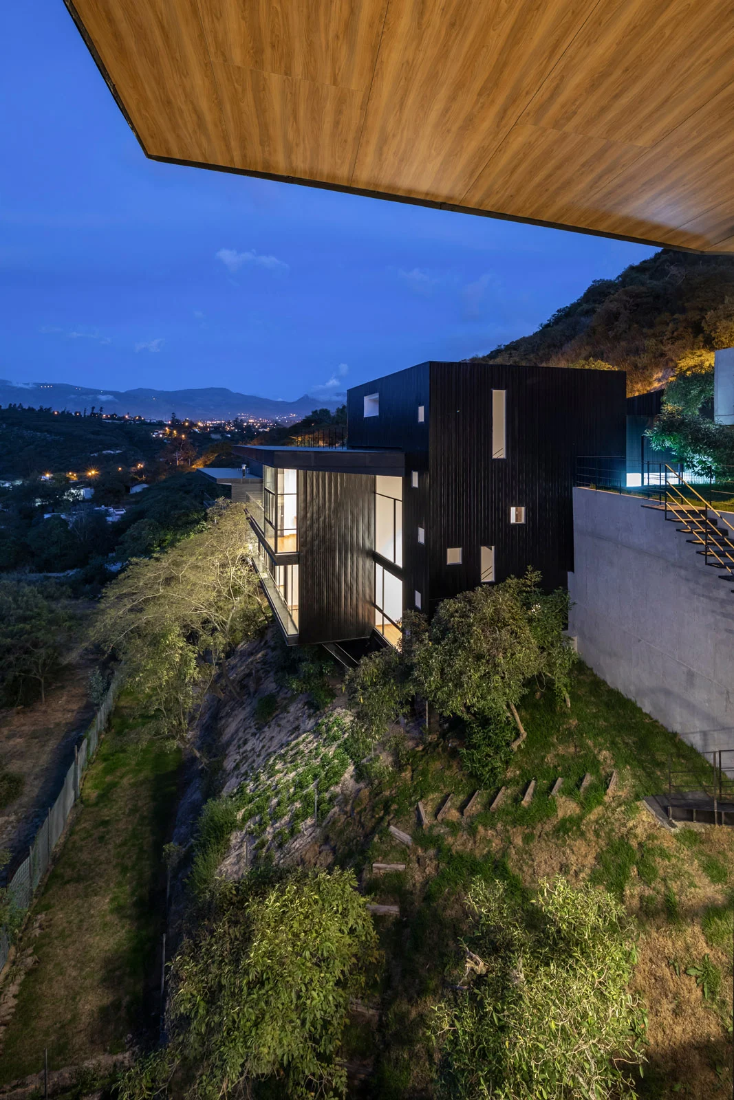 Vista nocturna de una de las tres viviendas independientes de Pillagua Barranco, implantada sobre la ladera de Cumbayá y diseñada por ENDARA ARQUITECTOS.