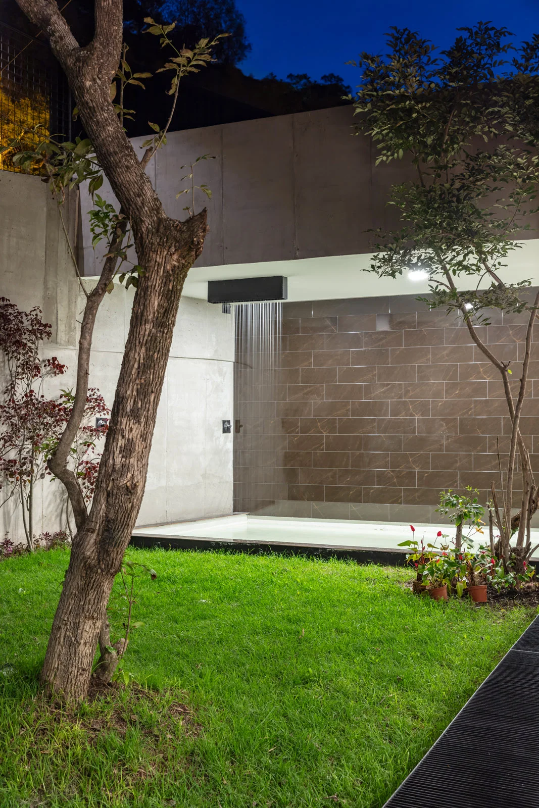 Patio posterior de una de las tres viviendas independientes de Pillagua Barranco, con espejo de agua, jardín y vegetación integrada al proyecto. Diseñada por ENDARA ARQUITECTOS en Cumbayá