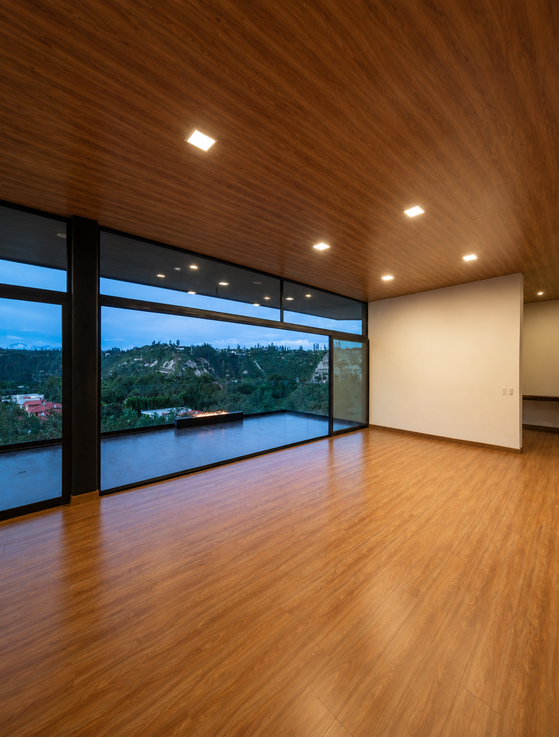 spacio interior de una vivienda de Pillagua Barranco con grandes ventanales hacia el paisaje de Cumbayá, techo revestido en madera y piso de madera natural. Proyecto de ENDARA ARQUITECTOS.
