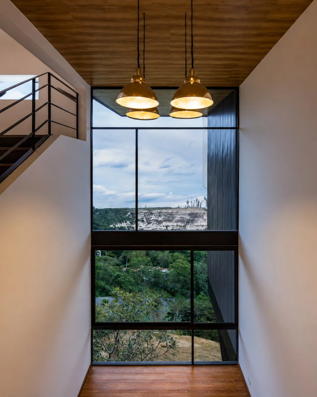 Sala de estar de una de las tres viviendas independientes de Pillagua Barranco, abierta al paisaje de Cumbayá mediante una gran fachada acristalada. Proyecto diseñado por ENDARA ARQUITECTOS.