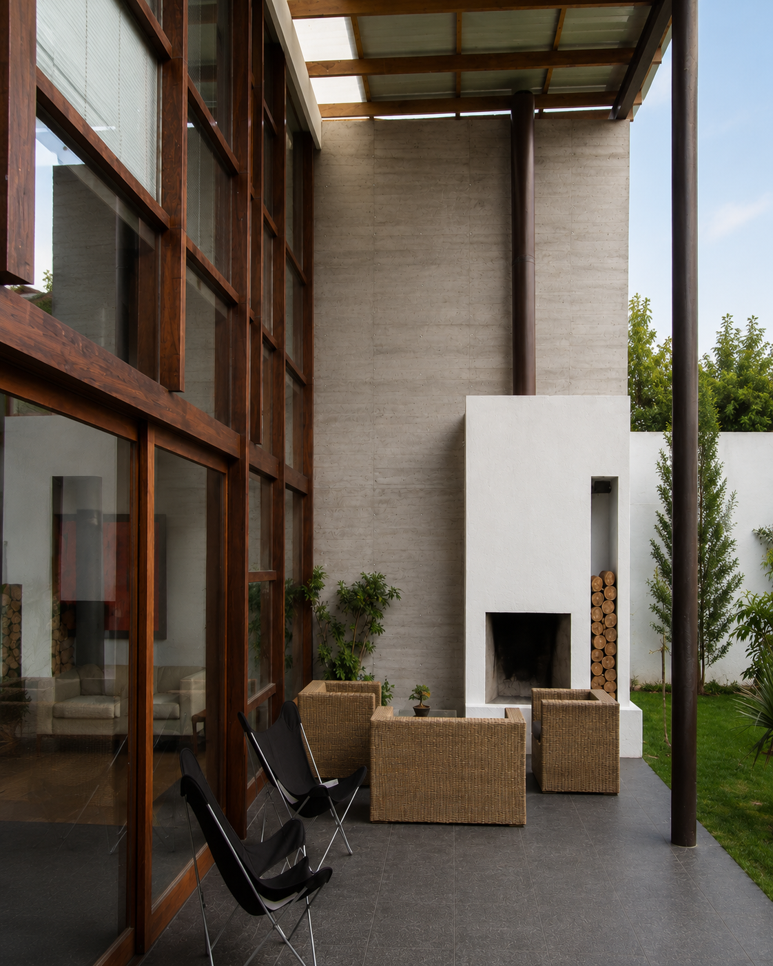 Casa Pillagua, porche de doble altura con chimenea y ventanas con marcos de madera. Diseñado por Endara Arquitectos.