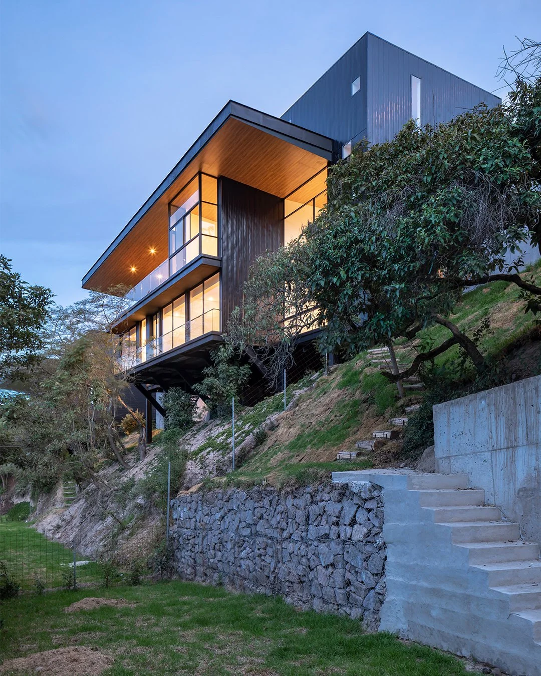 Vista exterior de una de las tres viviendas independientes de Pillagua Barranco, implantada sobre la ladera de Cumbayá y conectada al jardín mediante un recorrido de escaleras. Proyecto diseñado por ENDARA ARQUITECTOS.