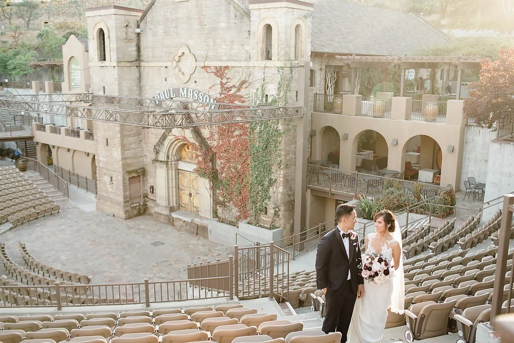 Bride and groom walking through The Mountain Winery amphitheater with vineyard views in Saratoga, California.