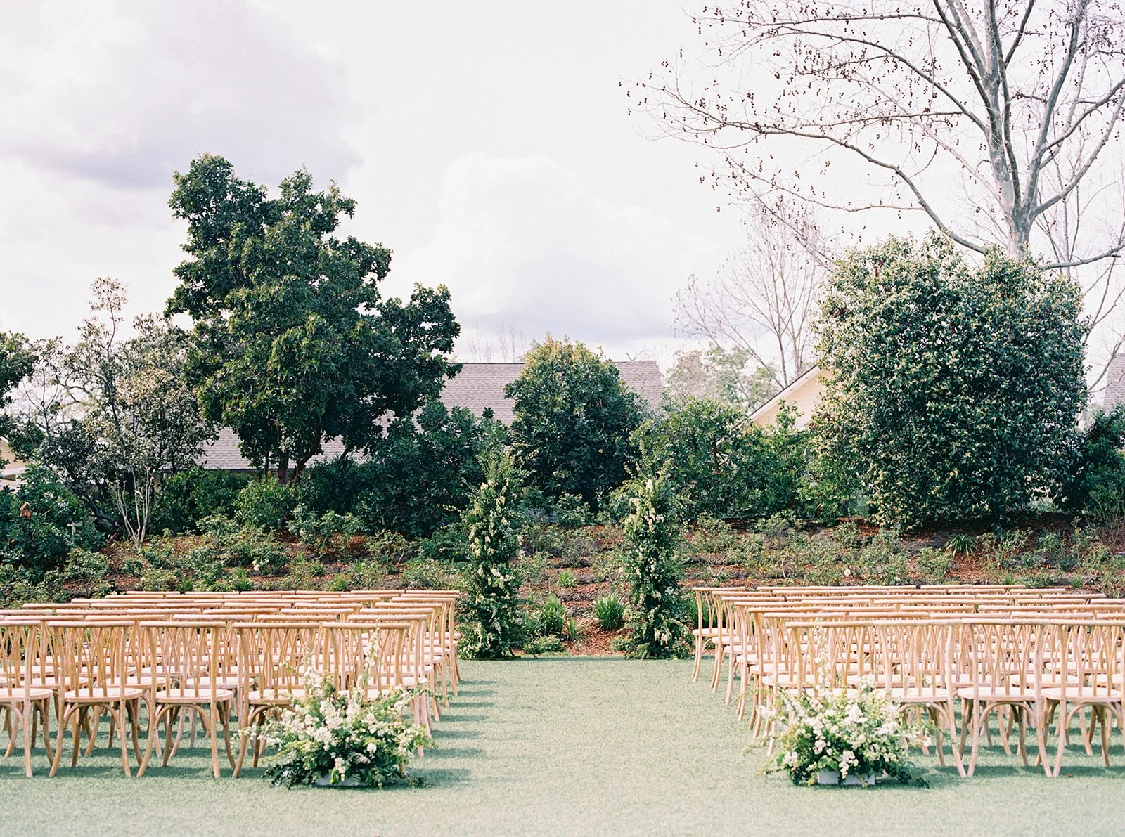 Outdoor ceremony setup at Solage in Napa Valley with natural greenery aisle arrangements and wooden chairs.
