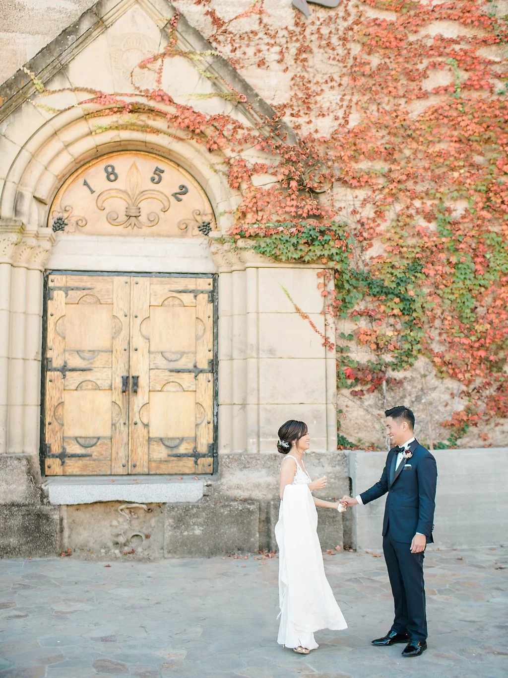 Bride and groom holding hands in front of ivy-covered stone architecture at The Mountain Winery in Saratoga.